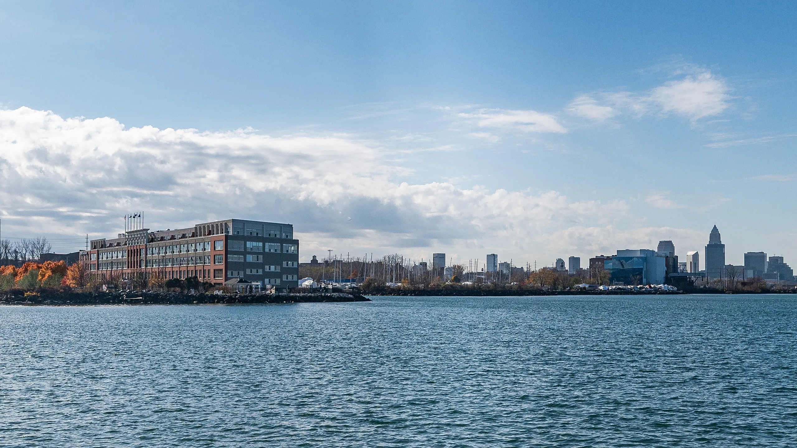Charming waterfront view with a stylish apartment building and city skyline, showcasing vibrant autumn colors.