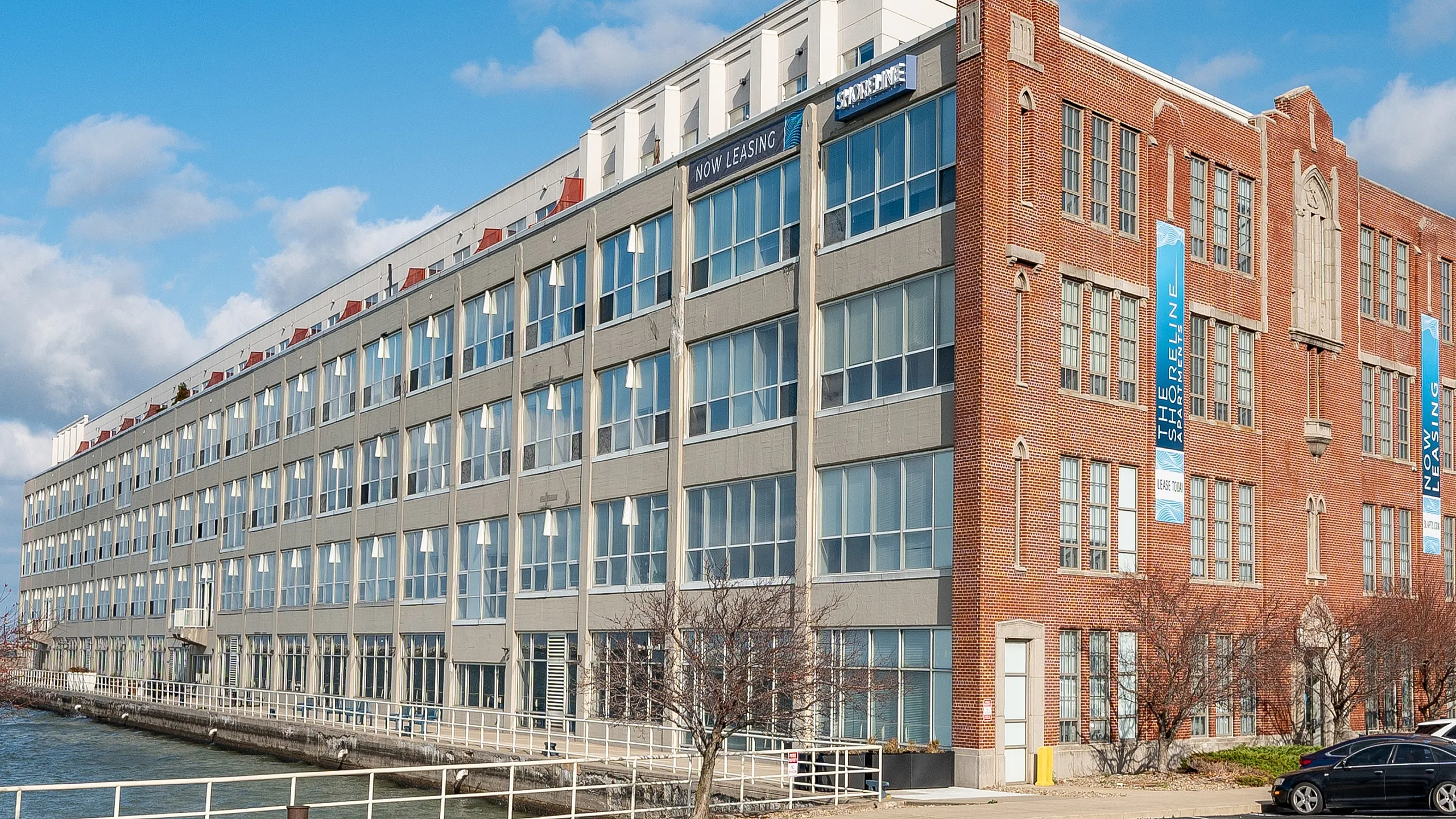 Charming waterfront apartment building with red brick accents and large windows, perfect for modern living with stunning views.