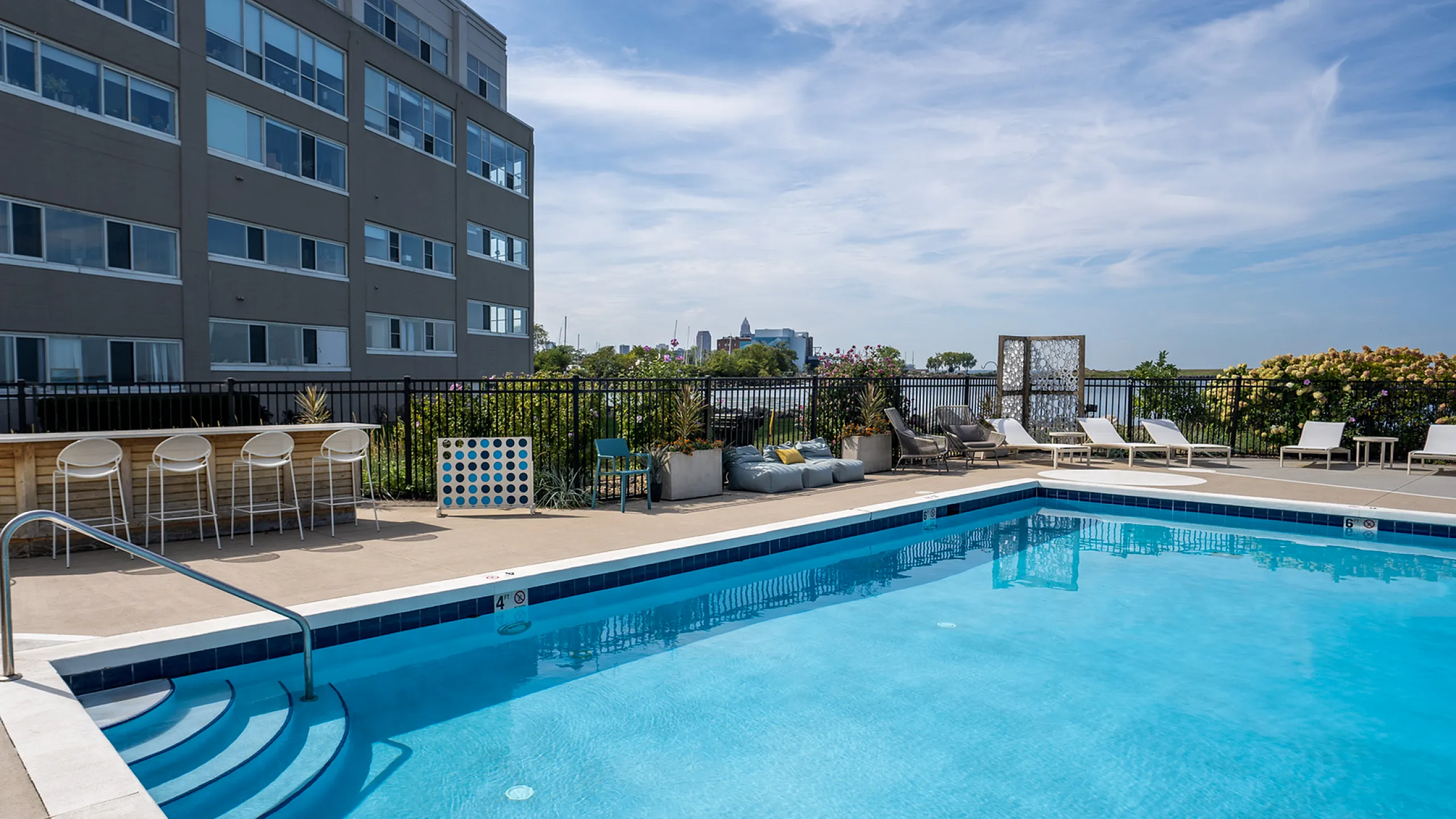 Luxurious rooftop pool area showcasing vibrant seating, lush greenery, and stunning city views perfect for relaxation and entertainment.