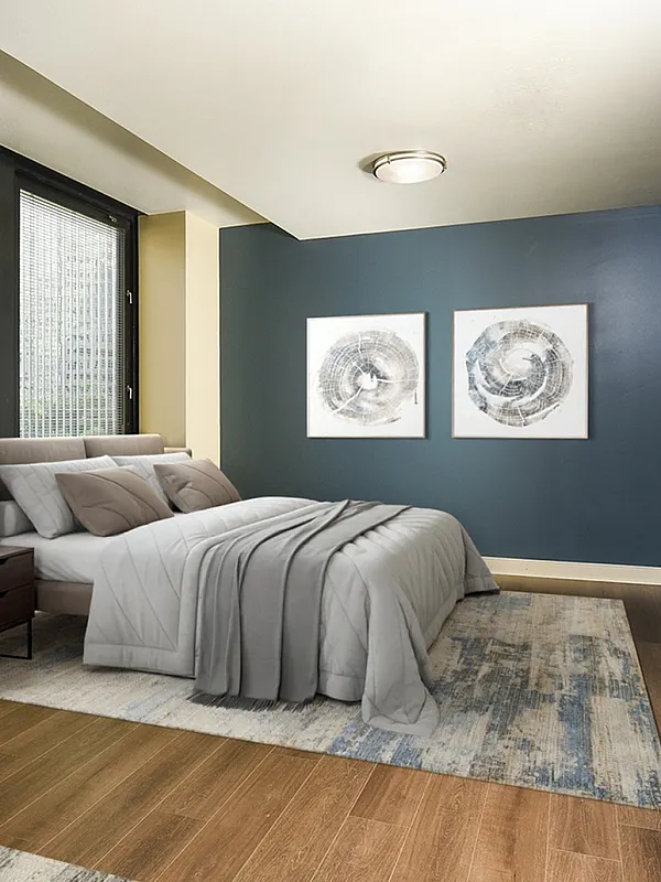Elegant bedroom with stylish decor, featuring a plush bed, large windows, and modern artwork. Cozy and inviting atmosphere with warm wood flooring.