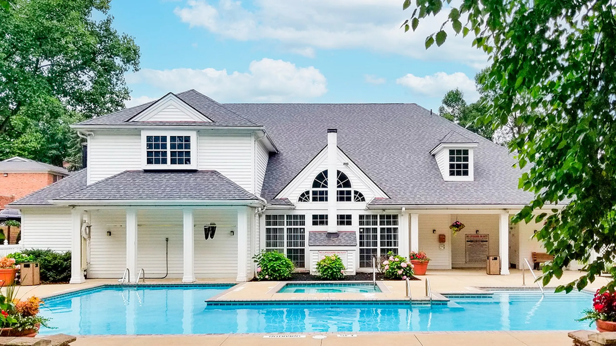 Elegant white house with a beautiful swimming pool and lush greenery, perfect for luxurious outdoor relaxation.
