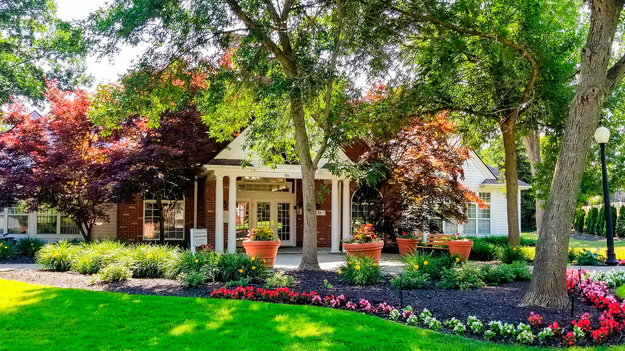 Charming apartment entrance surrounded by lush greenery and vibrant flowers, creating an inviting and serene atmosphere.