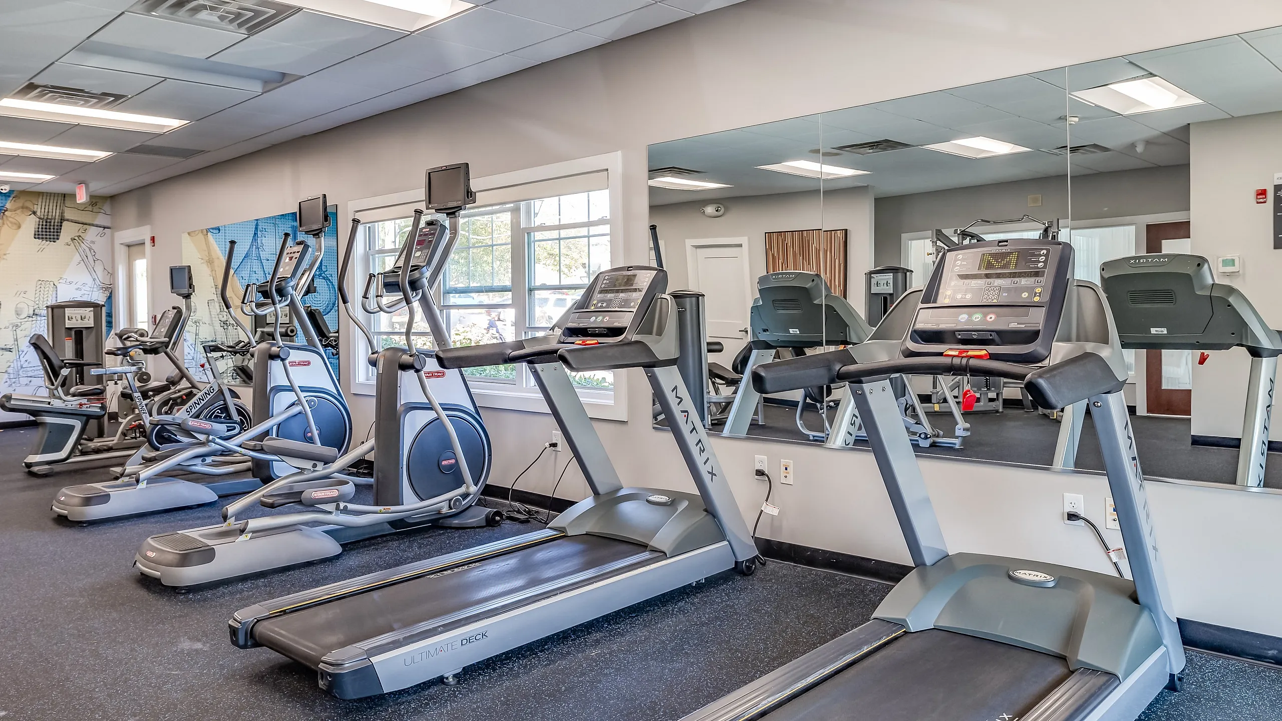 Bright and modern fitness center featuring state-of-the-art treadmills and exercise bikes with wall-to-wall mirrors, ideal for a healthy lifestyle.