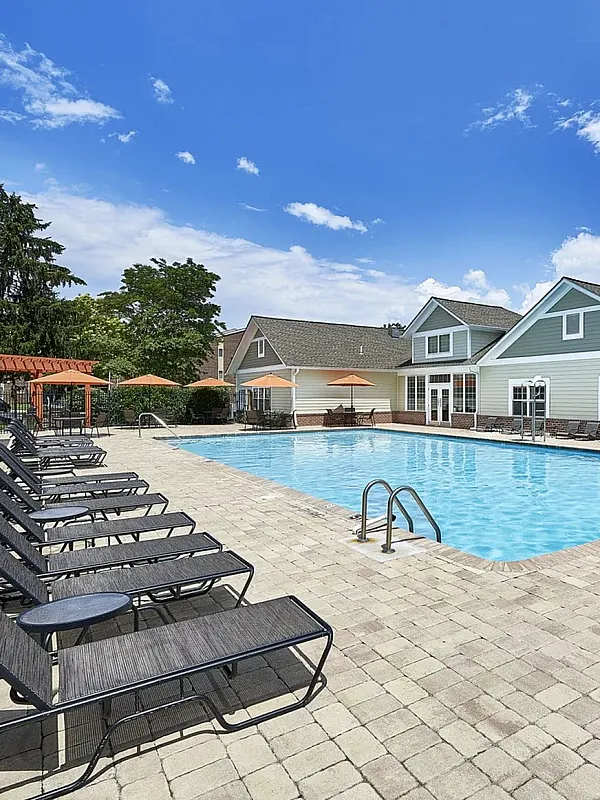 Inviting outdoor pool area with elegant lounge chairs and vibrant umbrellas against a picturesque blue sky.