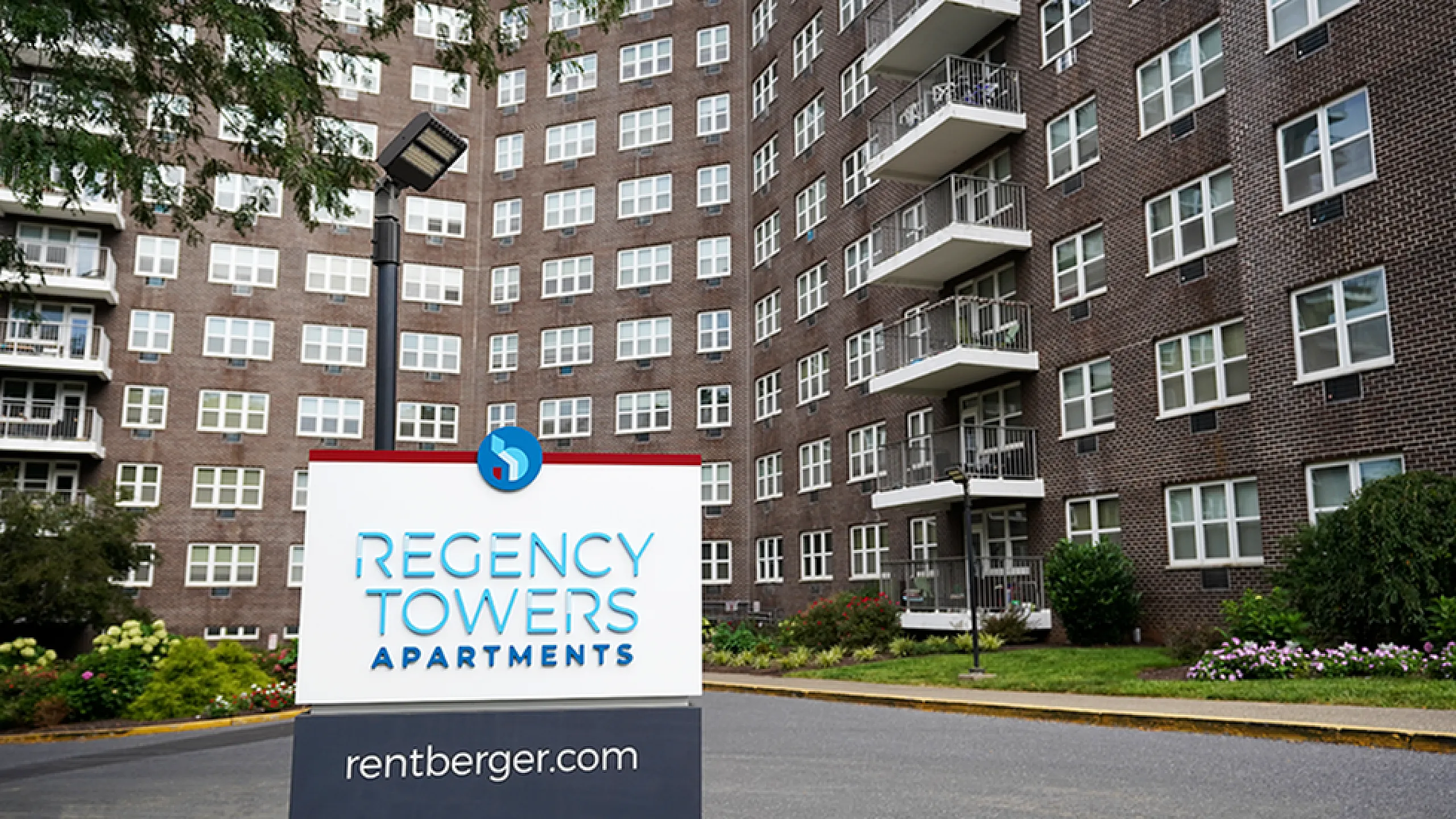 Elegant facade of Regency Towers Apartments with modern balconies and lush landscaping in a vibrant community setting.