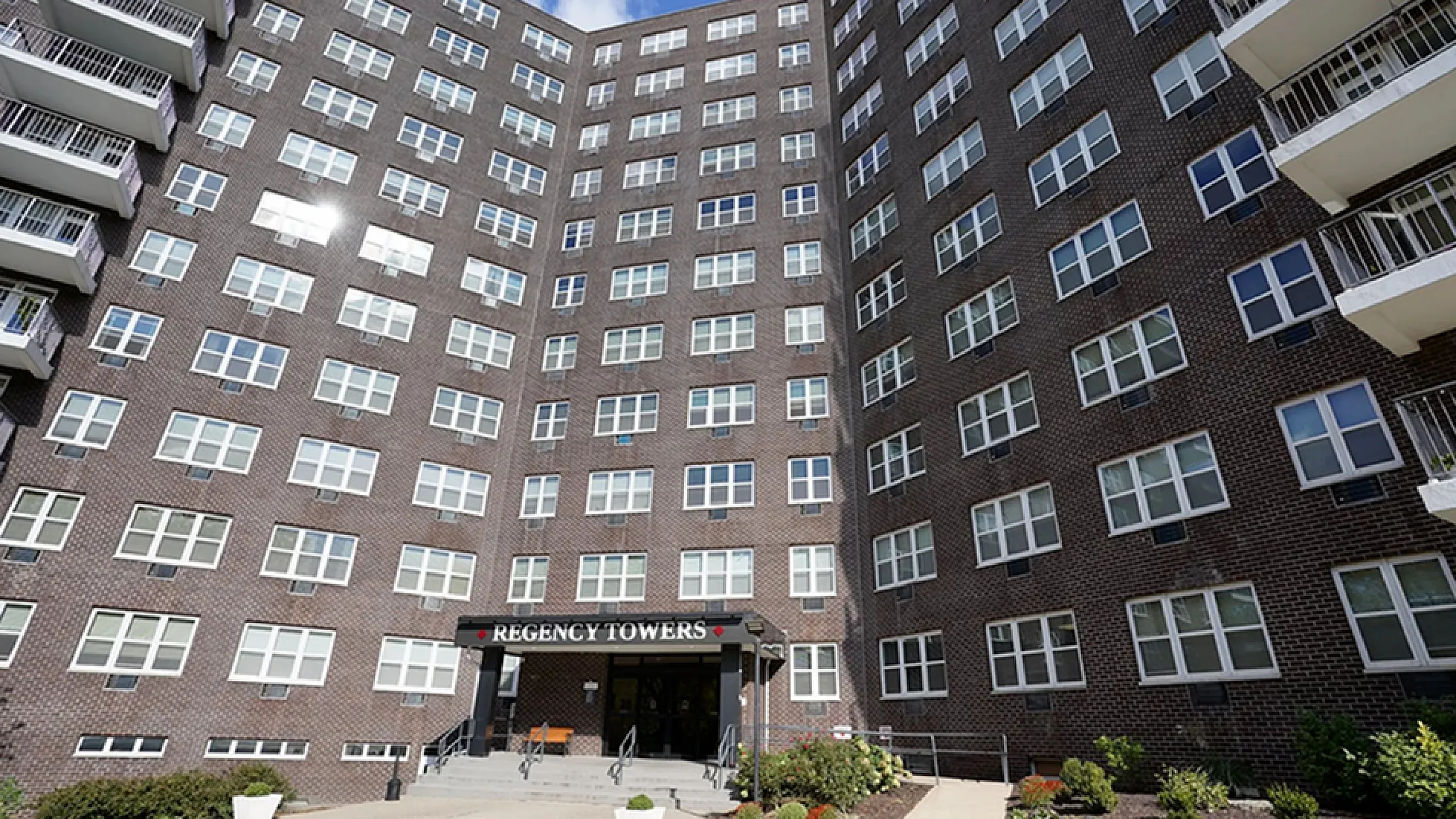 Elegant high-rise building, Regency Towers, showcasing modern architecture with large windows and inviting entrance, perfect for urban living.
