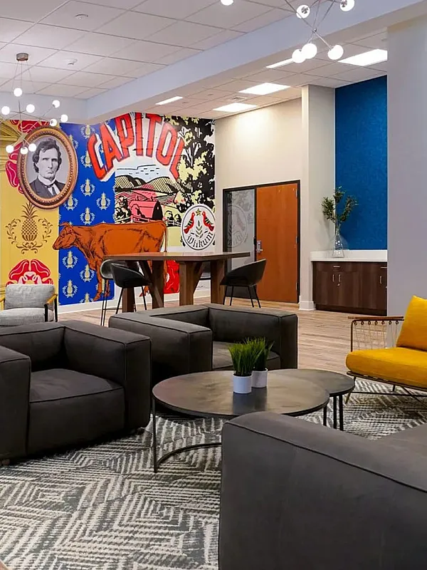 Vibrant lounge area featuring modern gray seating, a striking mural, and stylish lighting fixtures. Perfect for relaxation and social gatherings.
