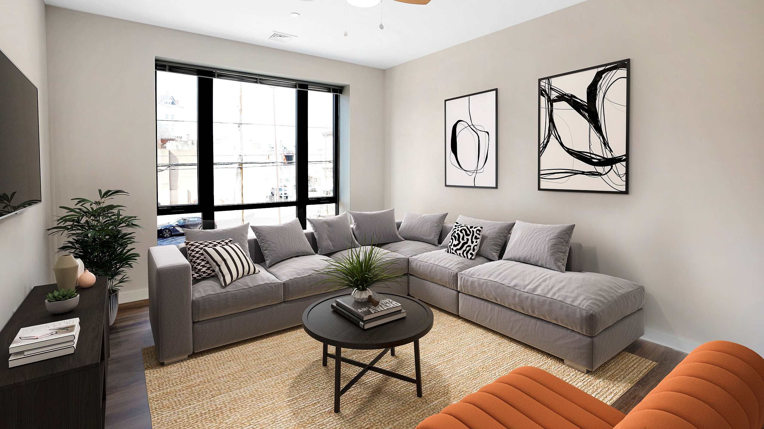 Modern living room with cozy gray sectional sofa, stylish black-and-white abstract art, and large panoramic windows offering abundant natural light.