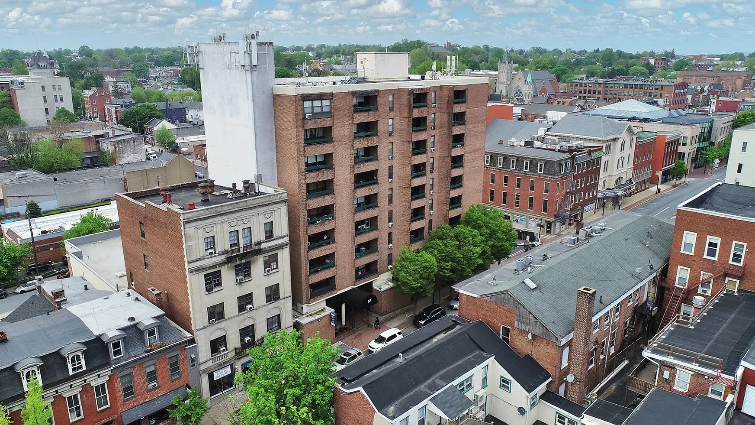 Charming urban apartment building nestled in a vibrant neighborhood, offering stunning cityscape views and lush greenery.