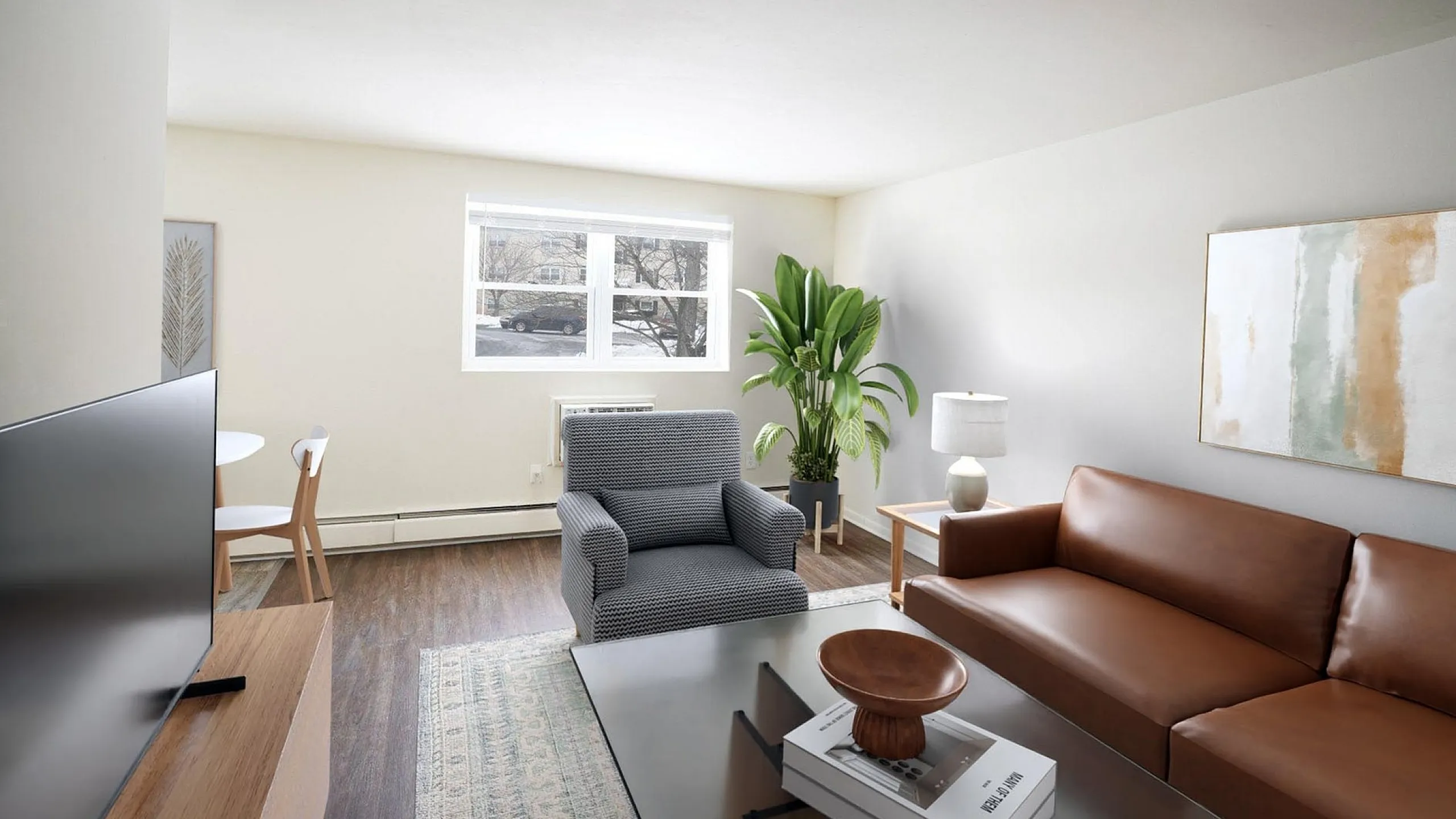 Bright and modern living room with sleek brown leather sofa, stylish armchair, large window with outside view, and vibrant green plant accent.