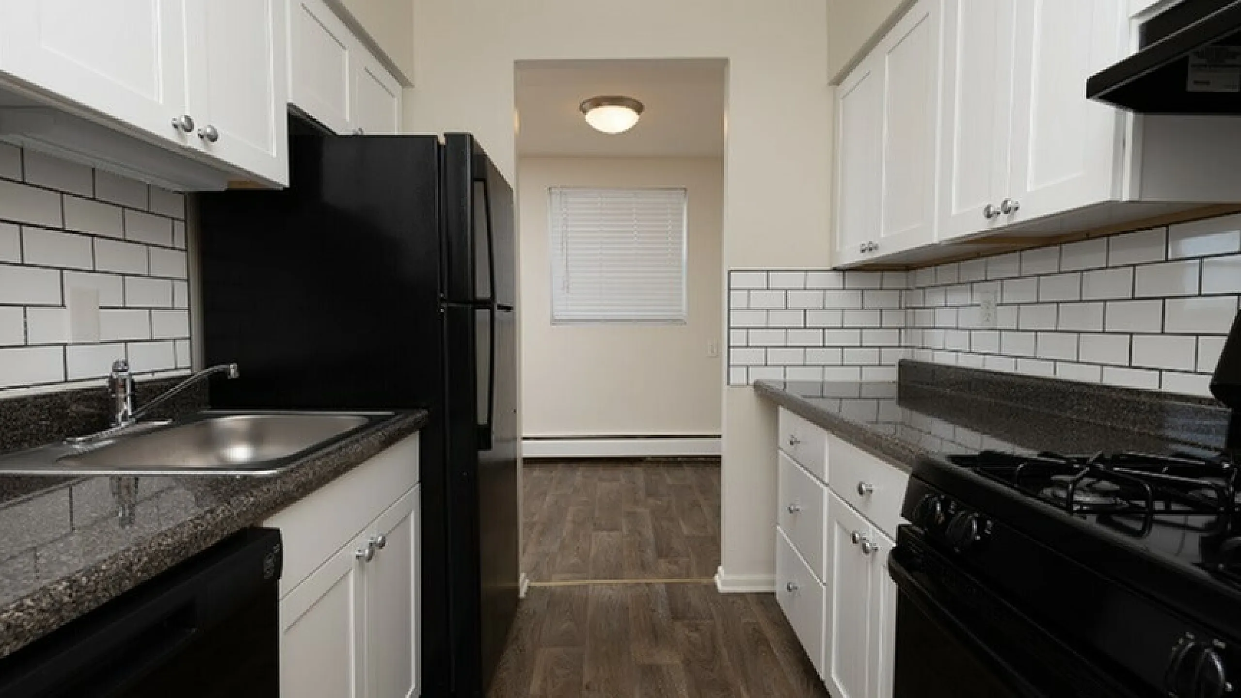 Modern kitchen with sleek black appliances, elegant white cabinetry, and stylish subway tile backsplash.