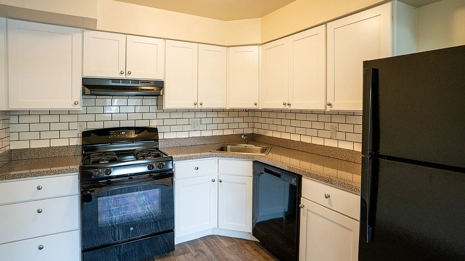 Modern kitchen with sleek black appliances, elegant white cabinetry, and stylish subway tile backsplash.