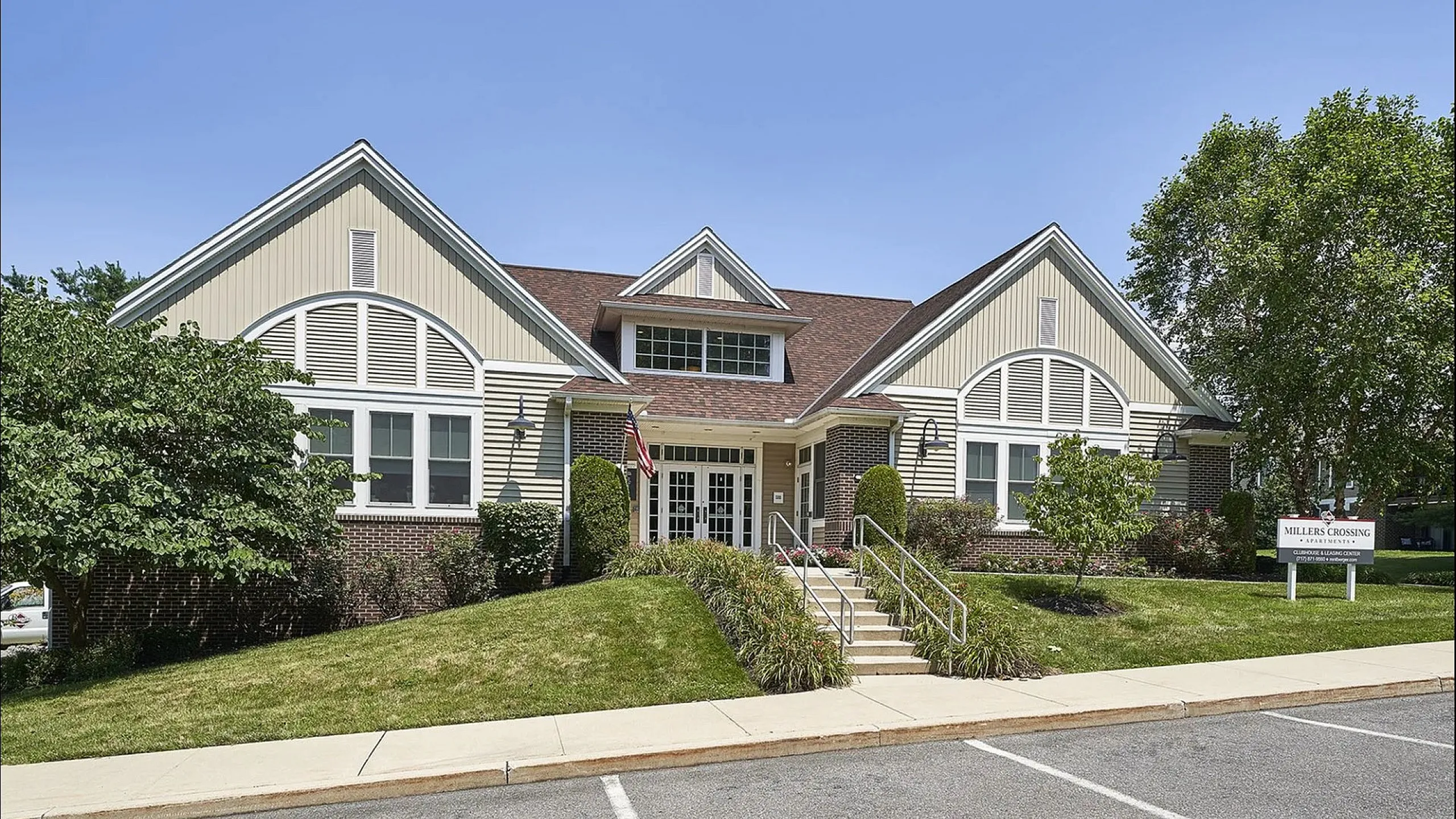 Charming residential building with a welcoming entrance, manicured lawns, and a classic architectural design at Millers Crossing Apartments.