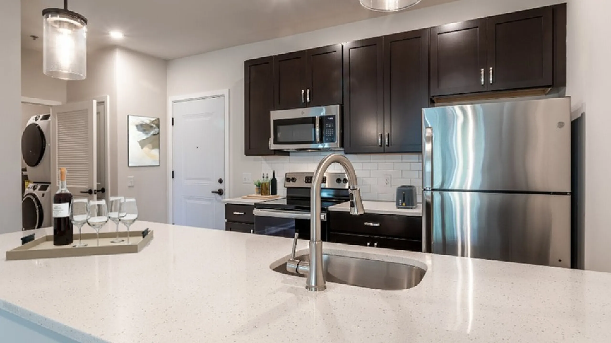 Modern kitchen with sleek stainless steel appliances, chic dark cabinets, and a stylish island, perfect for entertaining guests.