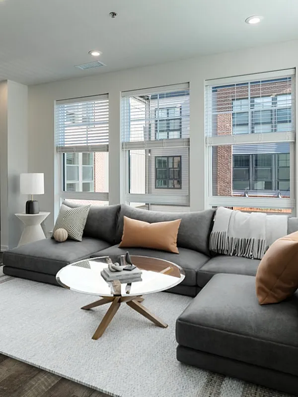 Bright and modern living room with large windows, elegant sofa, stylish decor, and a cozy dining area, perfect for urban living.