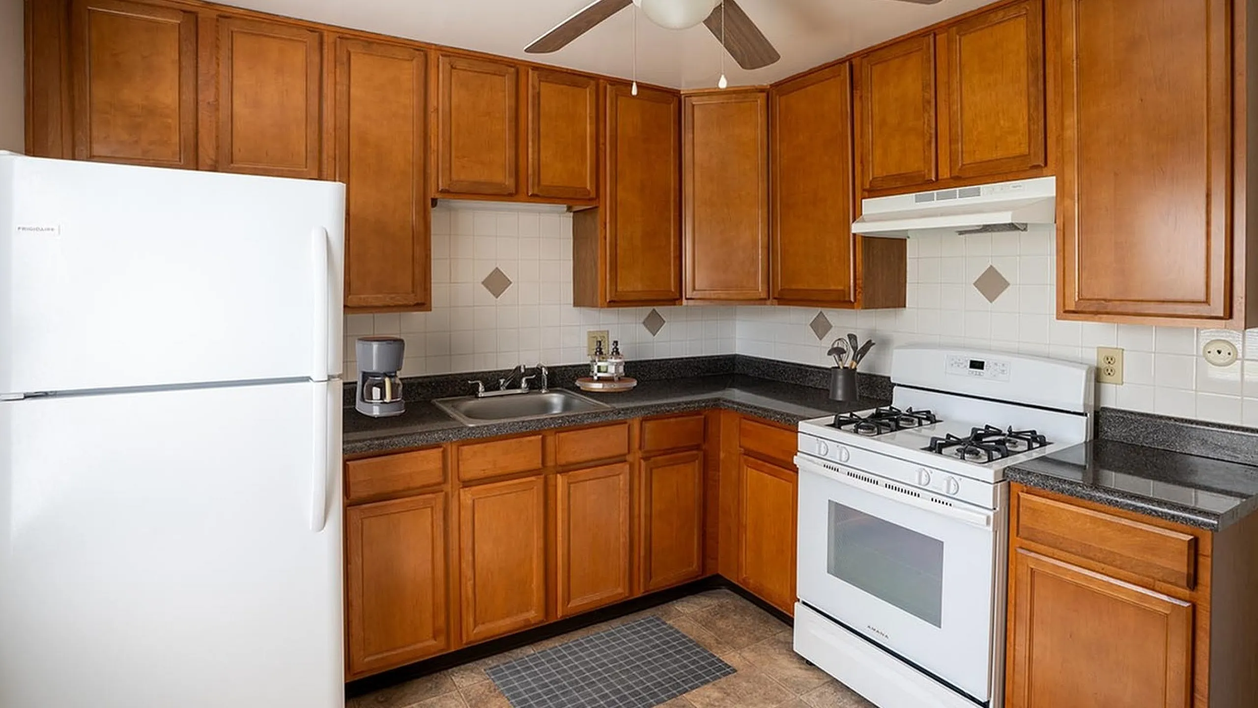 Inviting kitchen with rich wooden cabinets, sleek countertops, and modern appliances including a white fridge and stove.