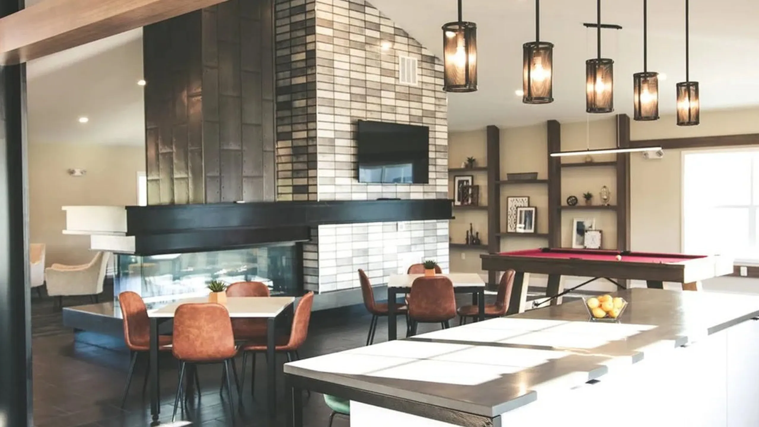 Luxurious open-plan living area featuring a modern fireplace, elegant dining space, and a chic pool table under stylish pendant lighting.