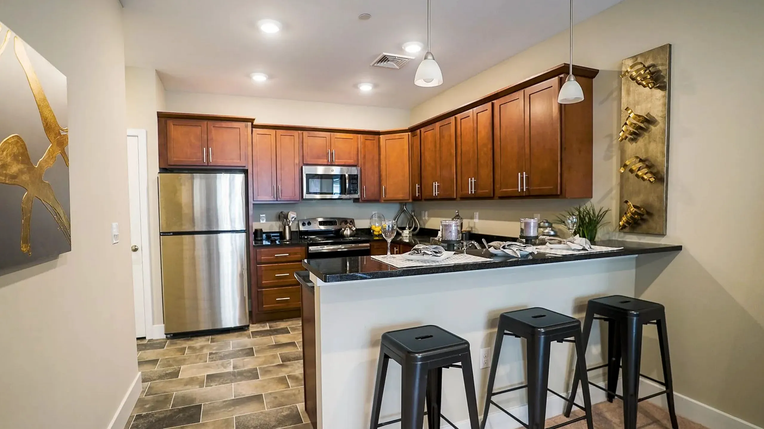 Modern kitchen with sleek stainless steel appliances, warm wooden cabinets, and inviting breakfast bar seating. Elegant pendant lighting adds a touch of sophistication.