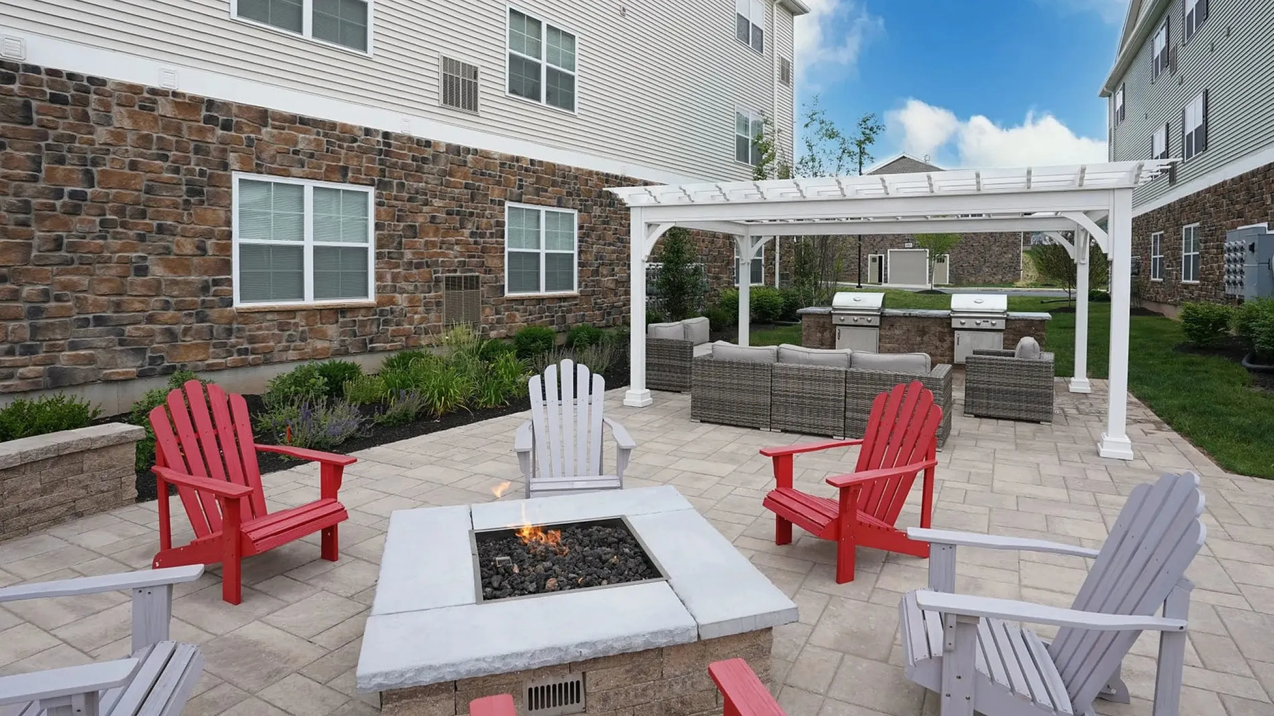 Inviting outdoor patio featuring cozy Adirondack chairs, a stylish fire pit, and modern pergola for ultimate relaxation.
