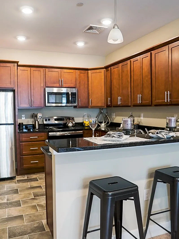 Contemporary kitchen with sleek stainless steel appliances, rich wooden cabinets, and a stylish breakfast bar complete with chic seating, perfect for modern living.