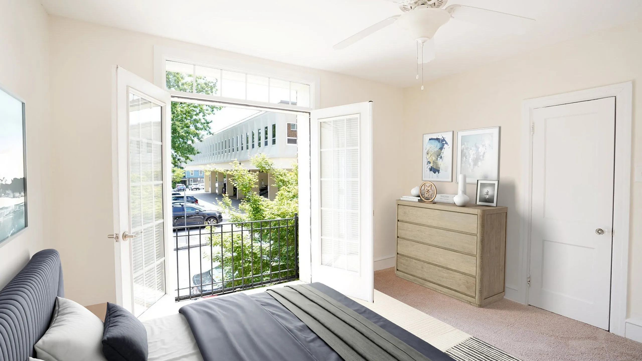 Bright and airy bedroom with elegant French doors opening to a cozy balcony, modern furnishings, and stylish decor.