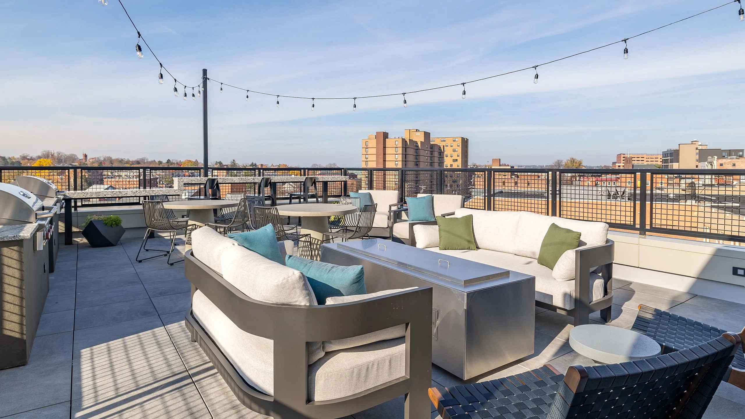 Modern rooftop terrace with cozy seating, string lights, and scenic city views, perfect for relaxation and entertaining.