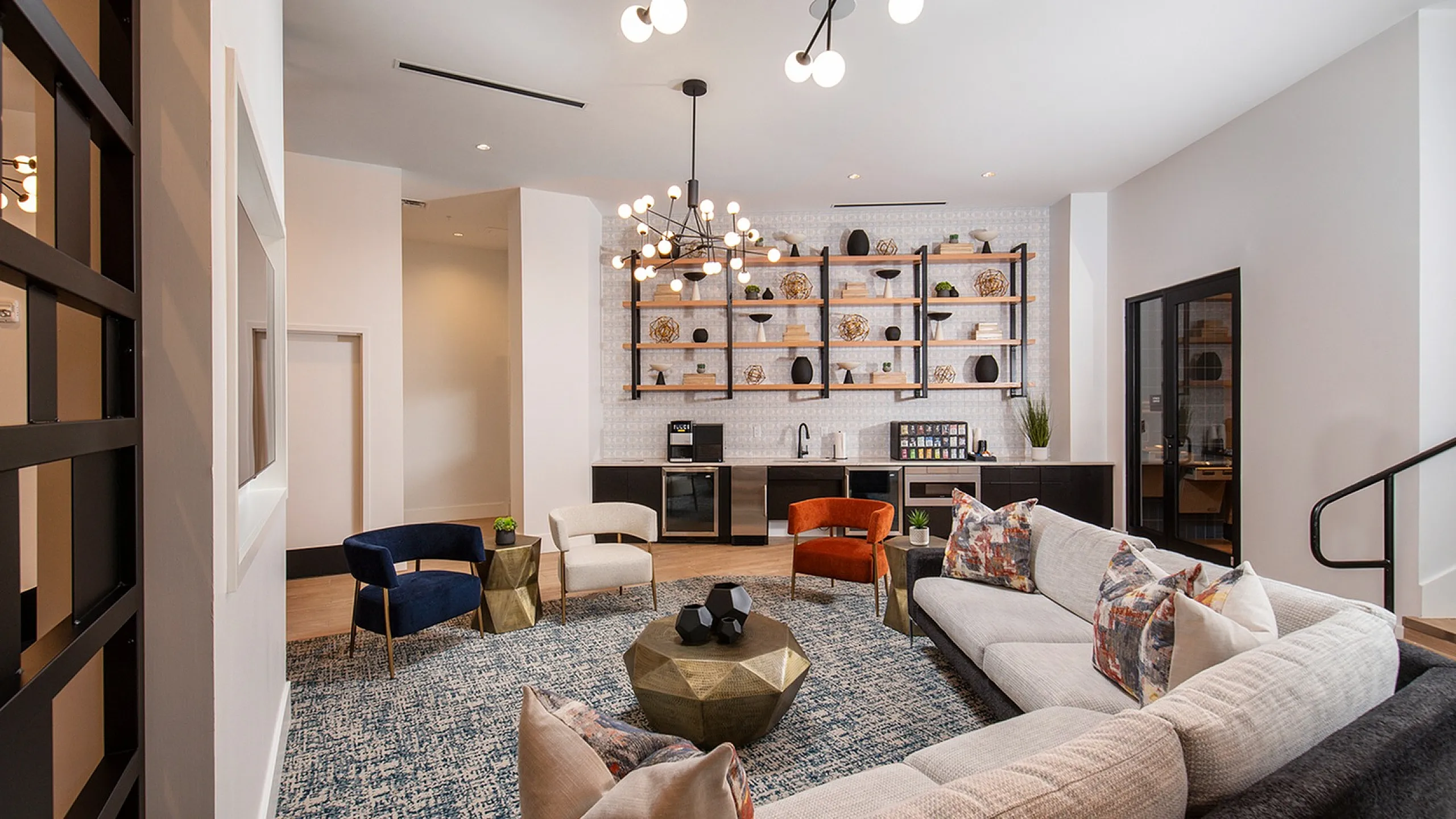 Modern lounge area with elegant decor, featuring a plush sectional sofa, chic armchairs, and a stylish bookshelf with contemporary accents.
