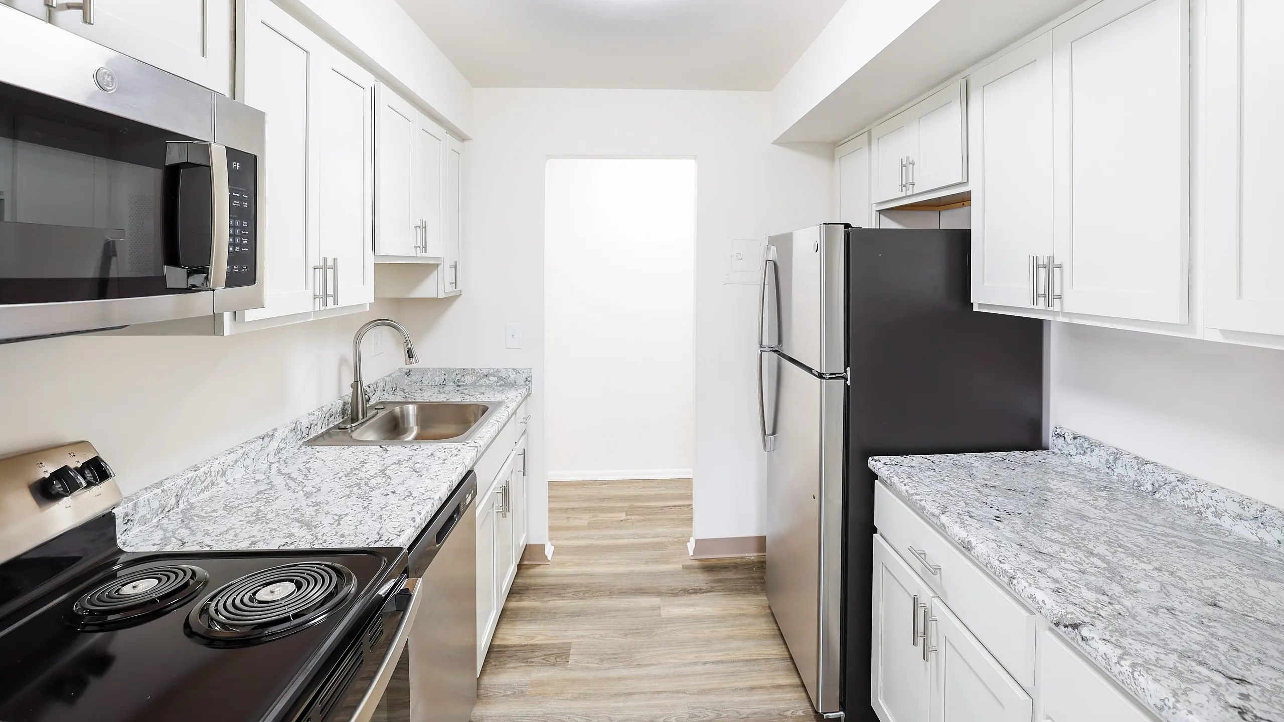 Modern kitchen with sleek stainless steel appliances, elegant granite countertops, and ample white cabinetry, perfect for culinary enthusiasts.