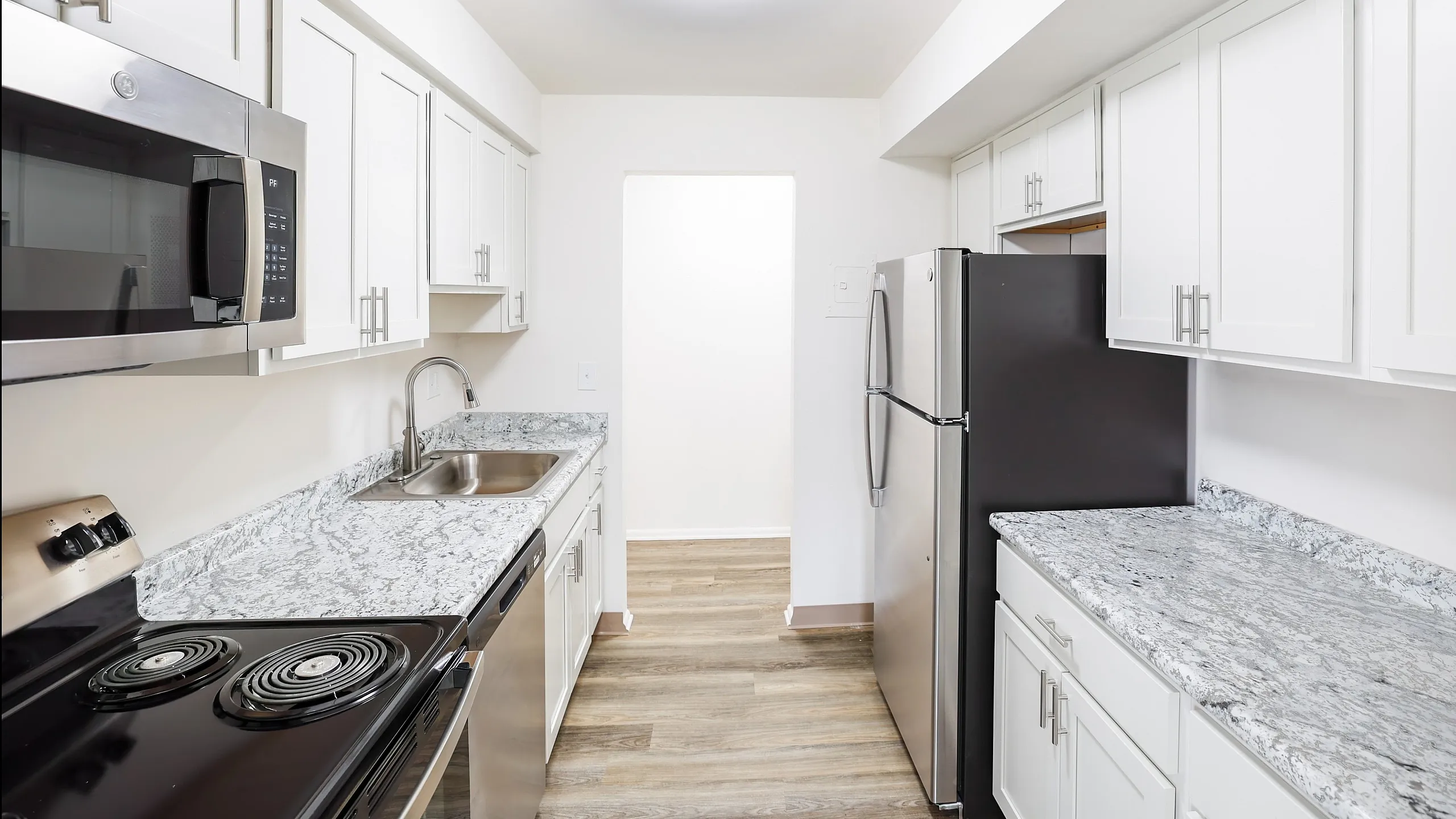 Modern kitchen with sleek stainless steel appliances, elegant granite countertops, and ample white cabinetry for a stylish culinary space.