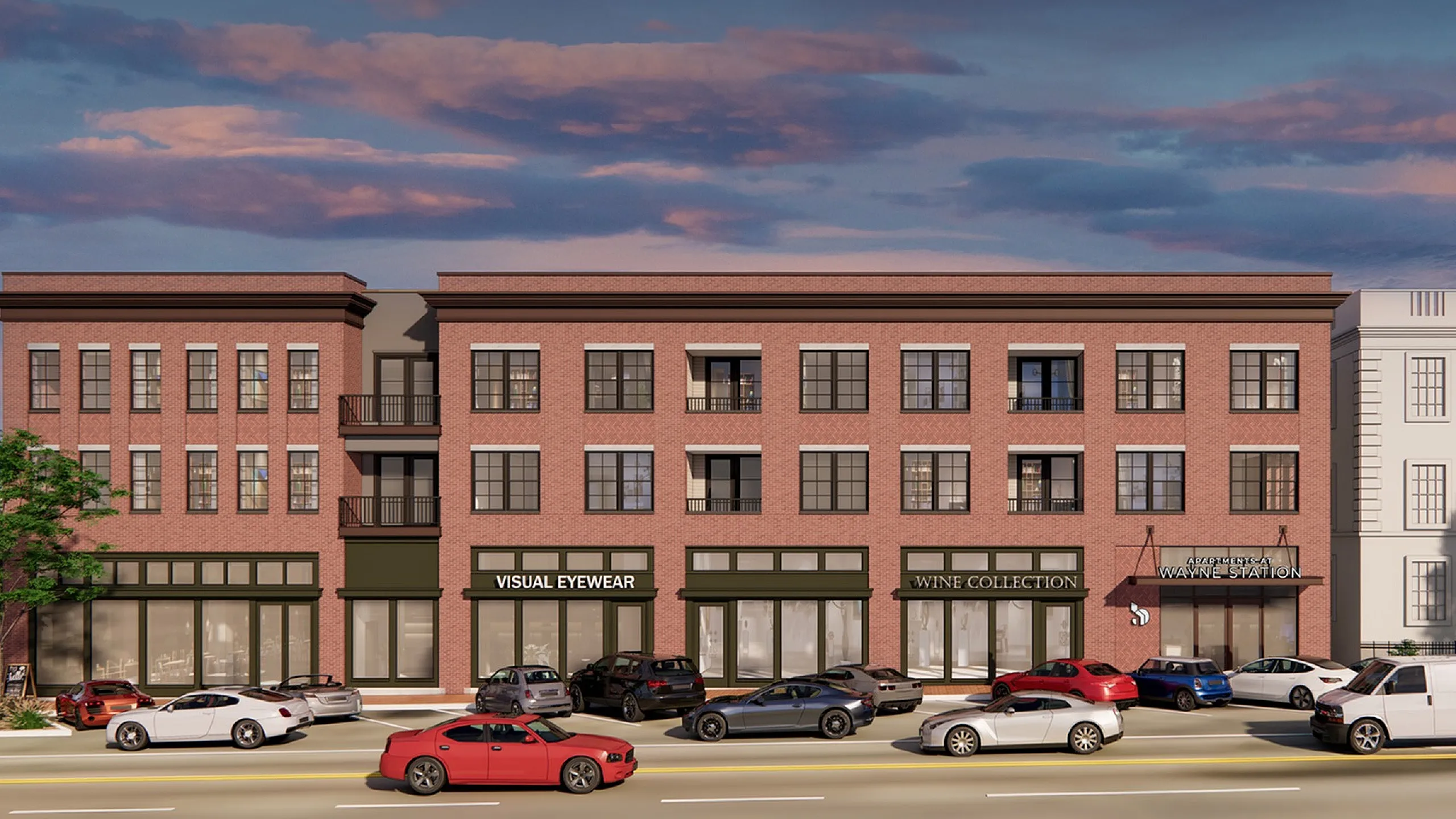 Charming three-story brick building with large windows and vibrant retail spaces, nestled under a picturesque evening sky.