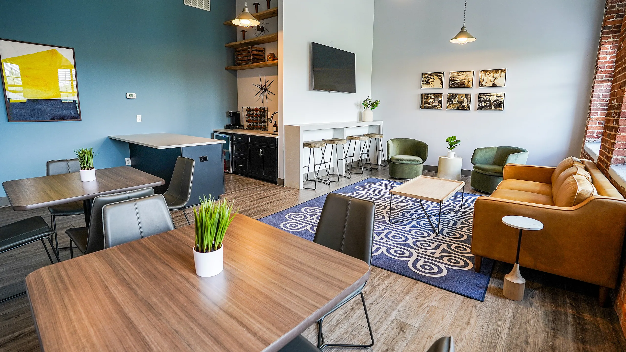 Chic communal space with modern furniture, vibrant blue accent wall, and natural lighting through large windows.