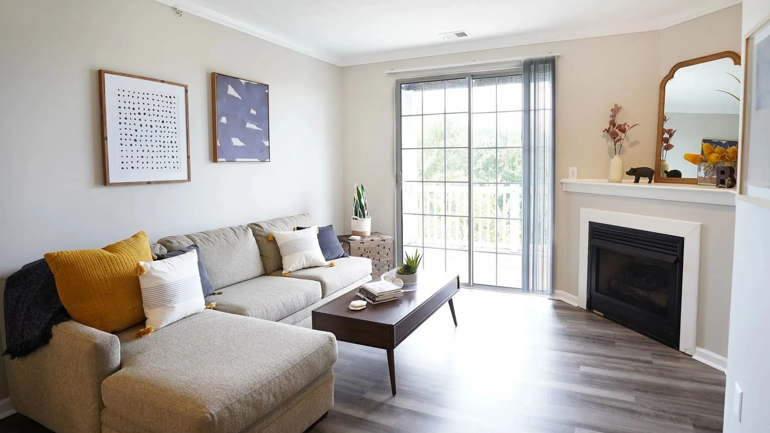 Bright and inviting living room featuring a cozy sectional sofa, stylish decor, and a fireplace. Large windows offer natural light and scenic views.