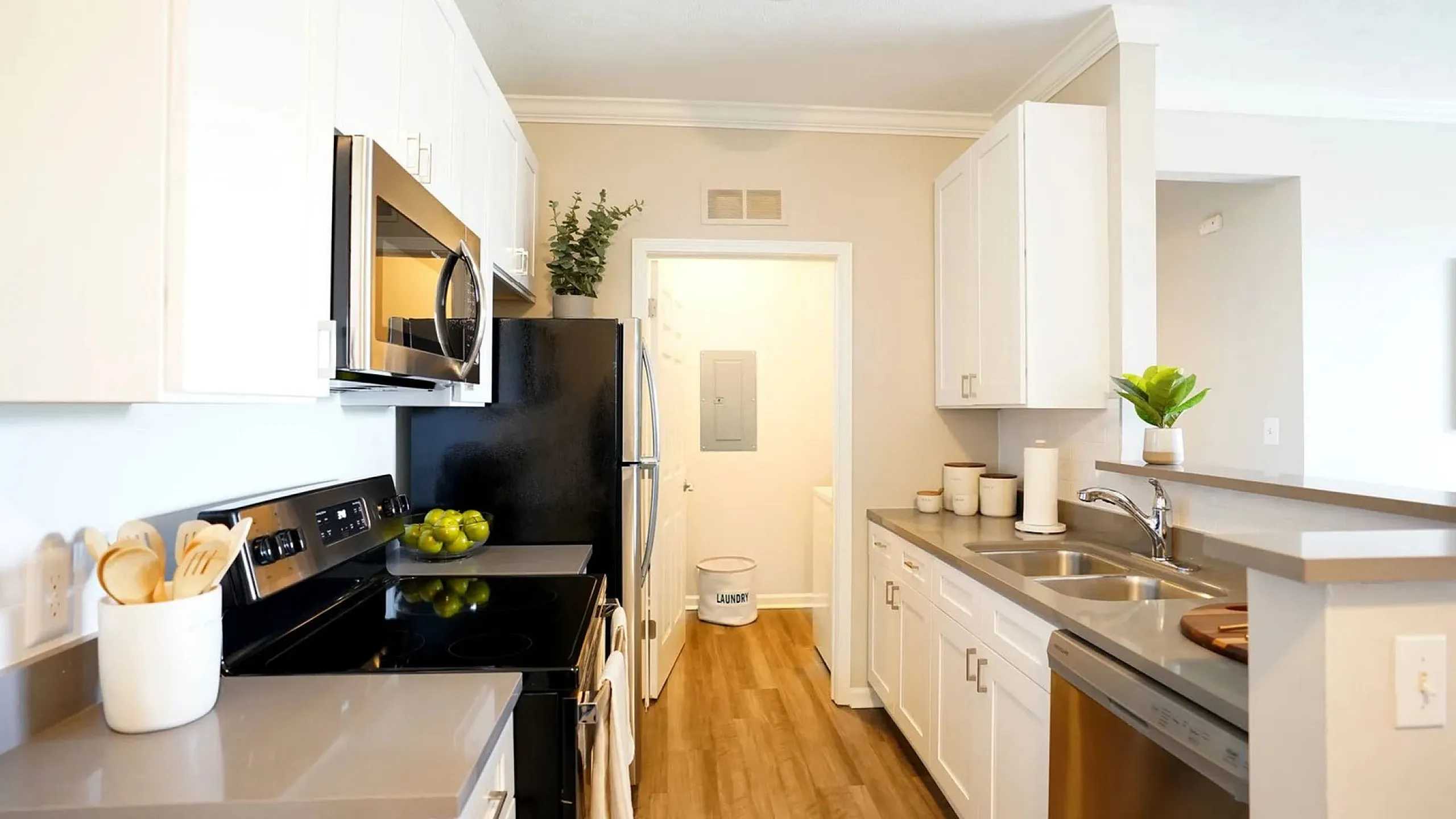 Modern kitchen with sleek gray countertops, stainless steel appliances, and white cabinetry, featuring a cozy kitchen layout with natural light and wooden flooring.