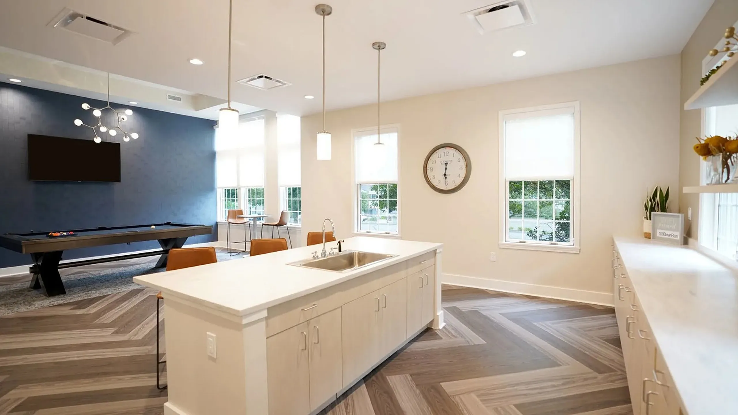 Modern open-plan space with a sleek kitchen island, stylish lighting, and a chic pool table area for entertainment.