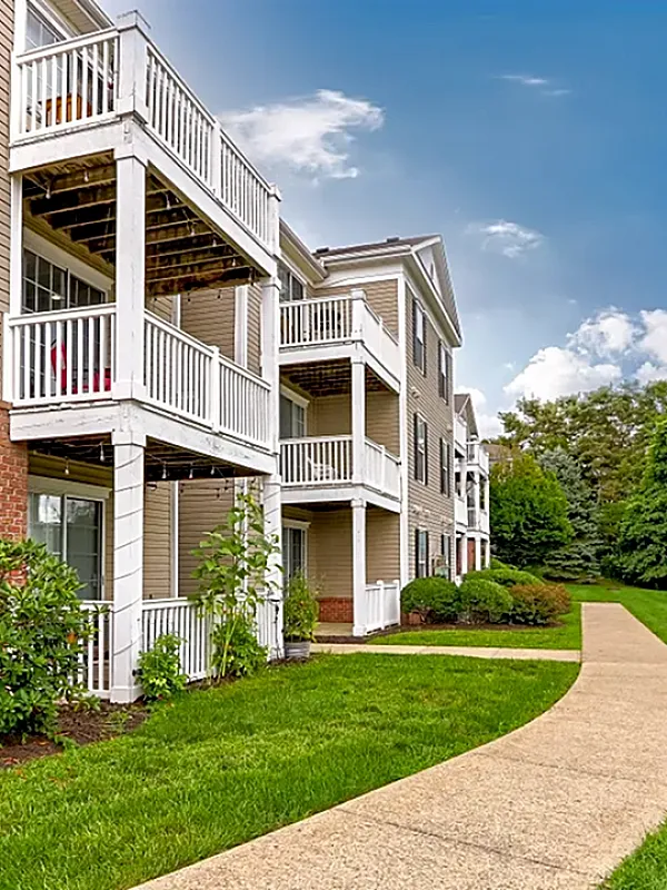 Charming apartment building with inviting balconies and lush green surroundings under a clear blue sky.