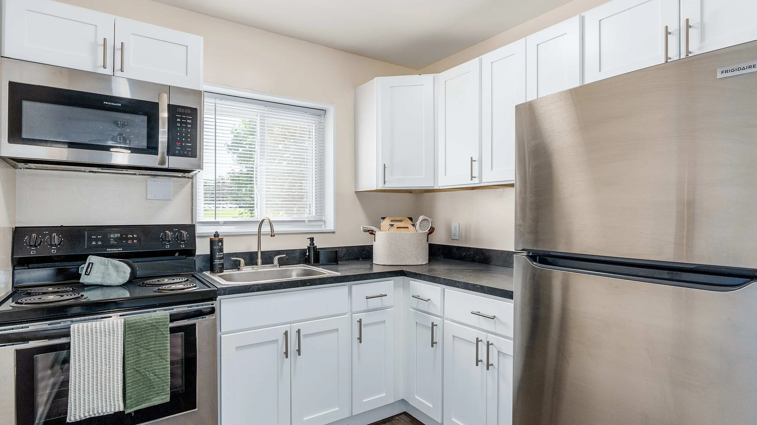 Modern kitchen featuring sleek stainless steel appliances, elegant white cabinetry, and a bright window illuminating the space.