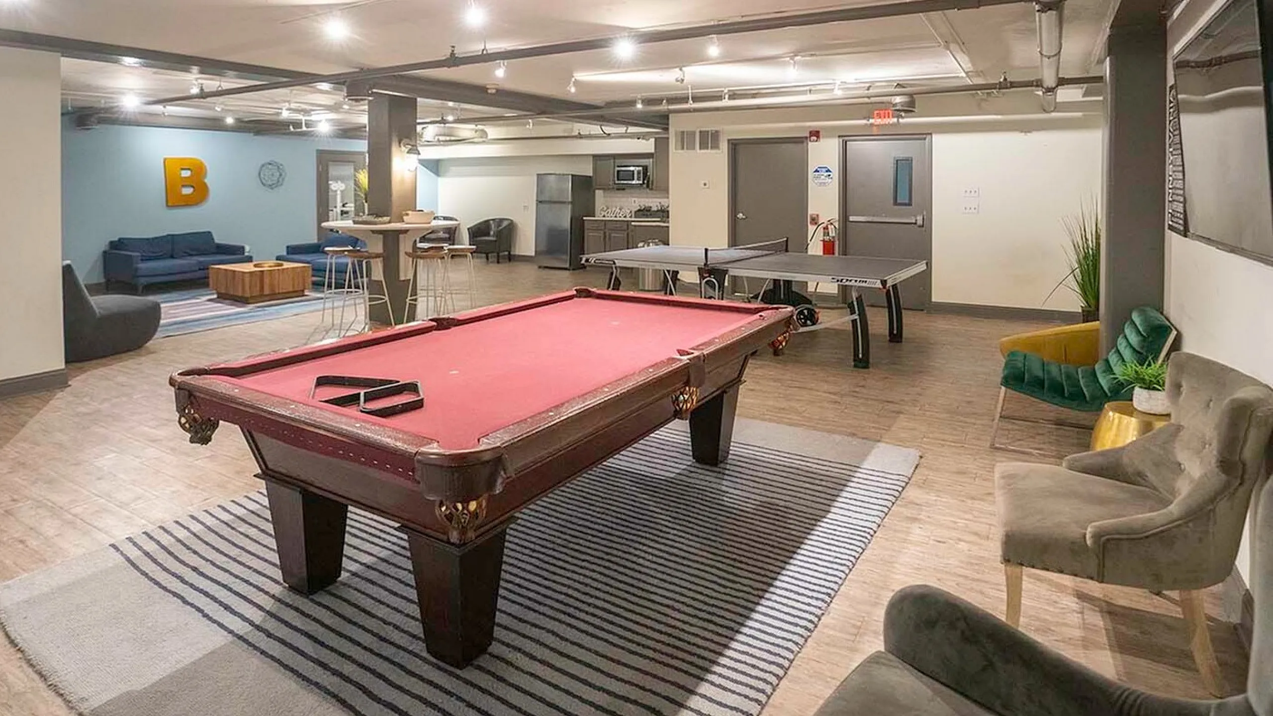Modern recreational room featuring a stylish pool table, cozy seating, vibrant decor, and a ping pong table, perfect for relaxation and entertainment.