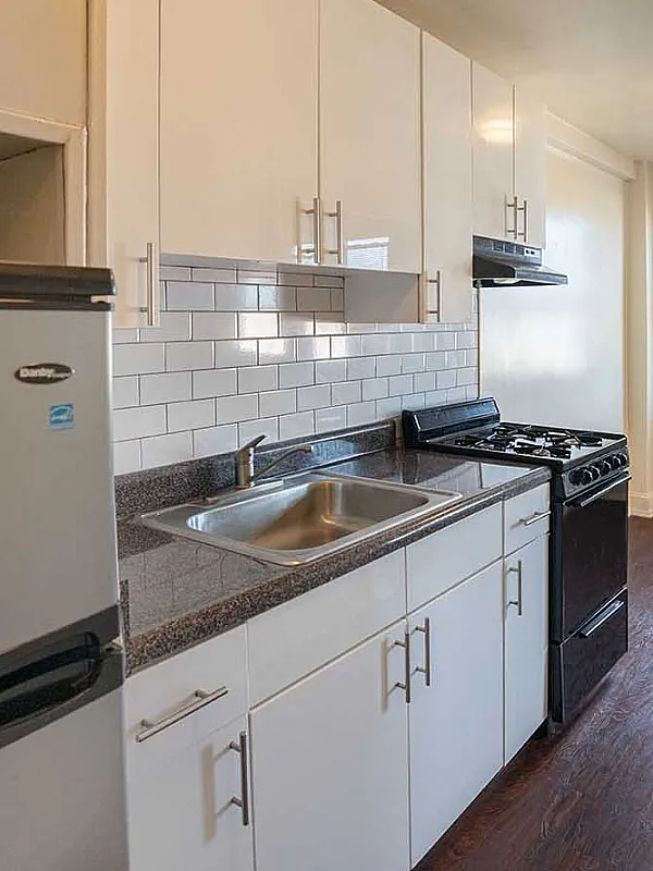 Bright and inviting kitchen with modern appliances, glossy white cabinetry, and warm wooden floors, perfect for culinary creativity.