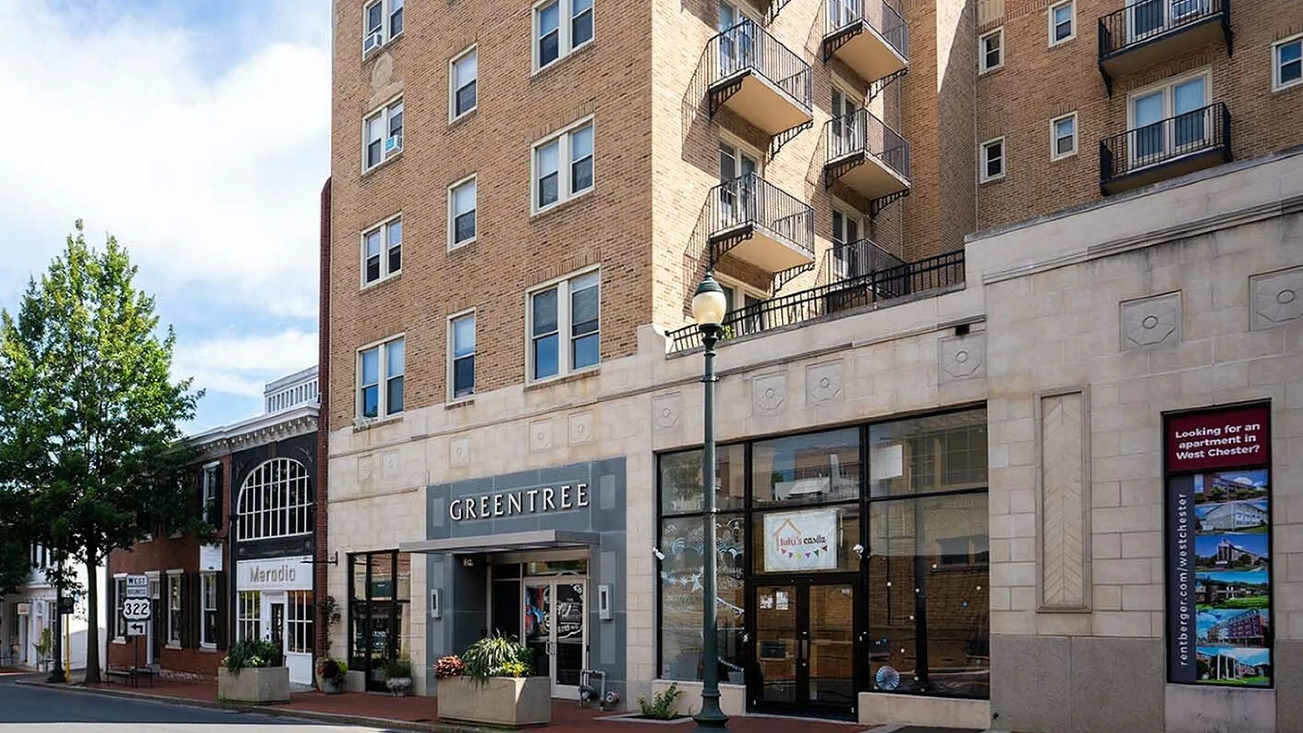 Charming urban apartment building with vintage brick facade and inviting balconies, located on a bustling street corner.