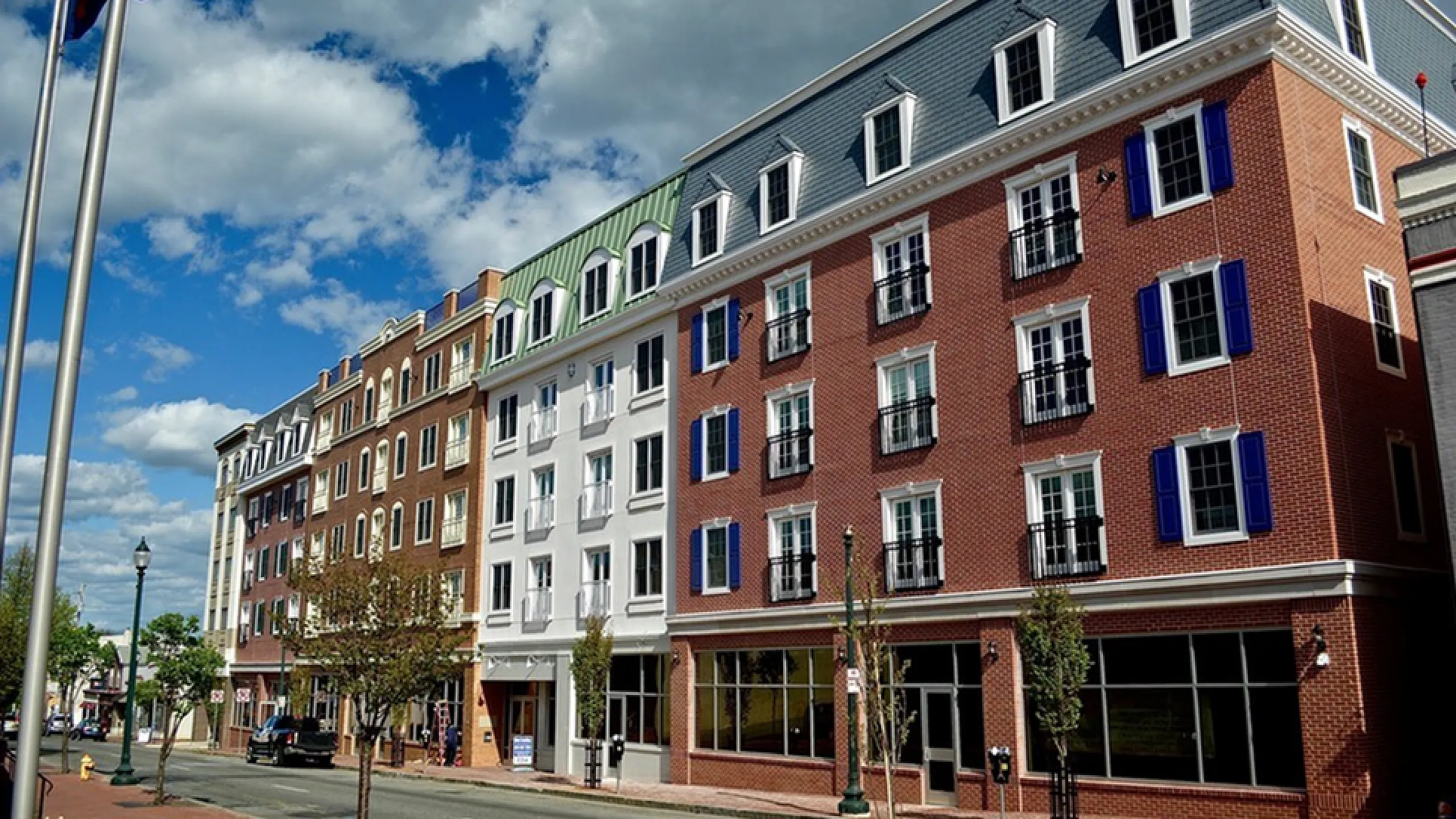 Charming urban apartment building with brick facade and elegant architecture, showcasing vibrant blue shutters against a sunny backdrop.