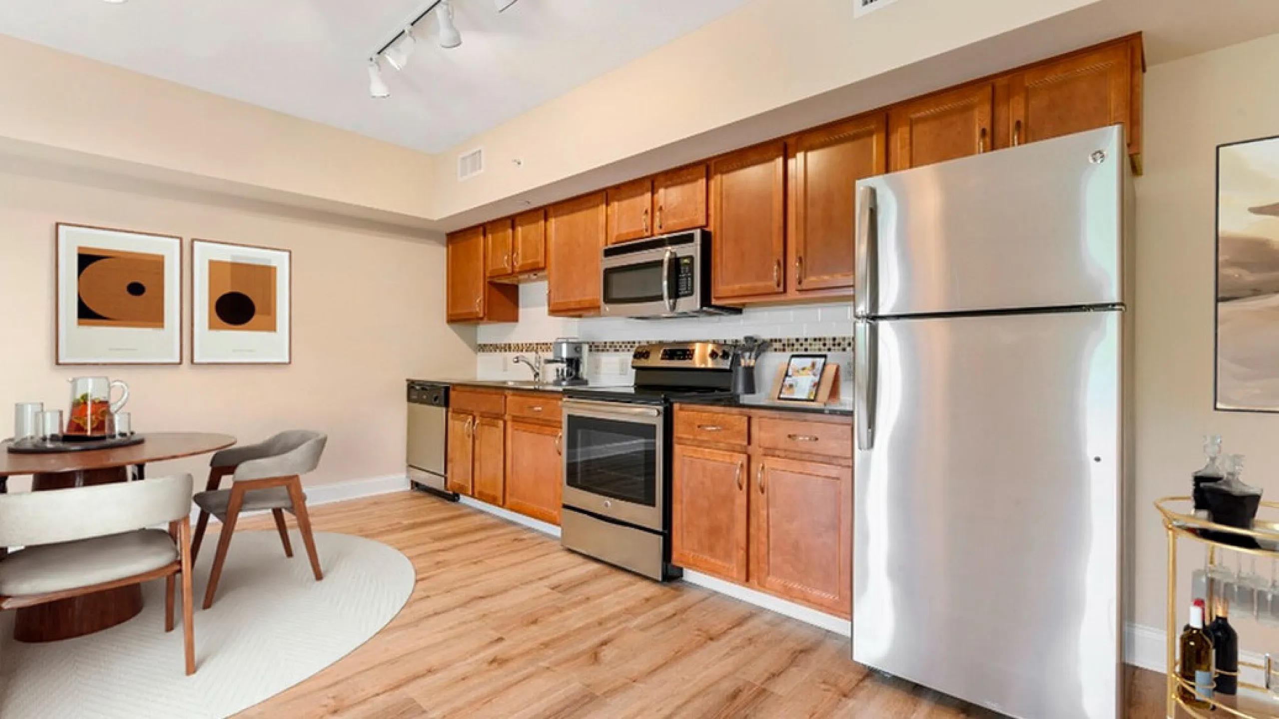 Elegant kitchen and dining area featuring modern stainless steel appliances, warm wooden cabinets, and chic decor art on the wall.