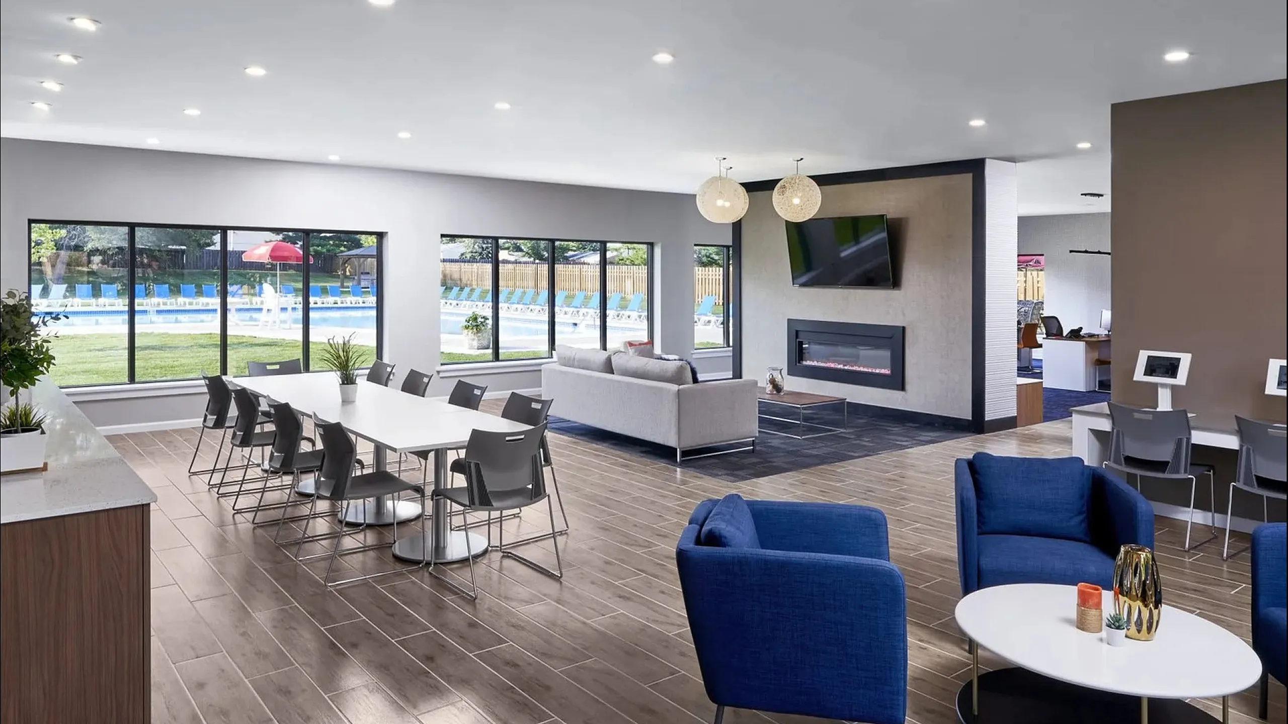 Modern communal area with sleek dining, comfortable seating, and large windows overlooking a scenic poolside.