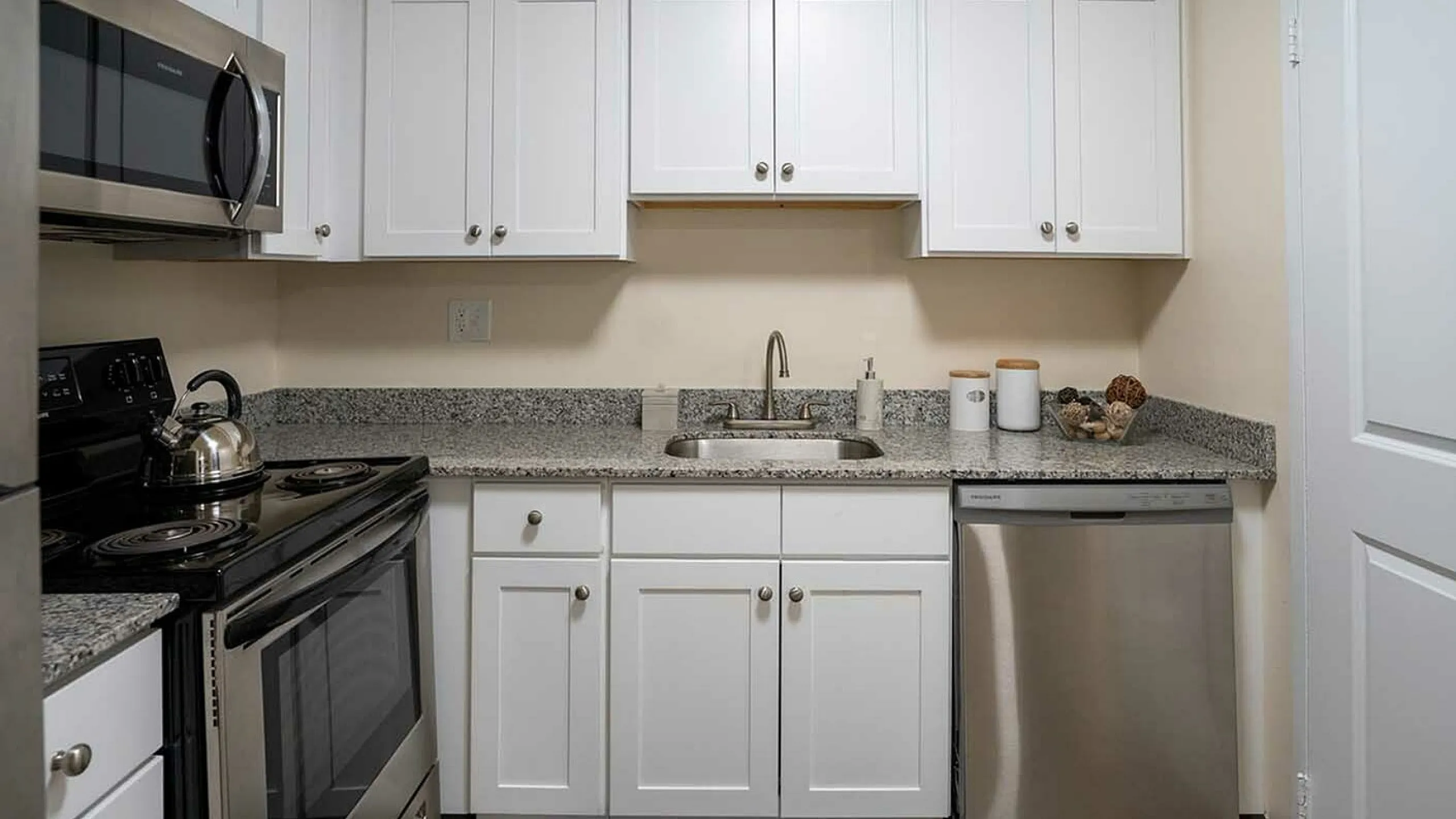 Modern kitchen with sleek stainless steel appliances, granite countertops, and stylish white cabinetry.