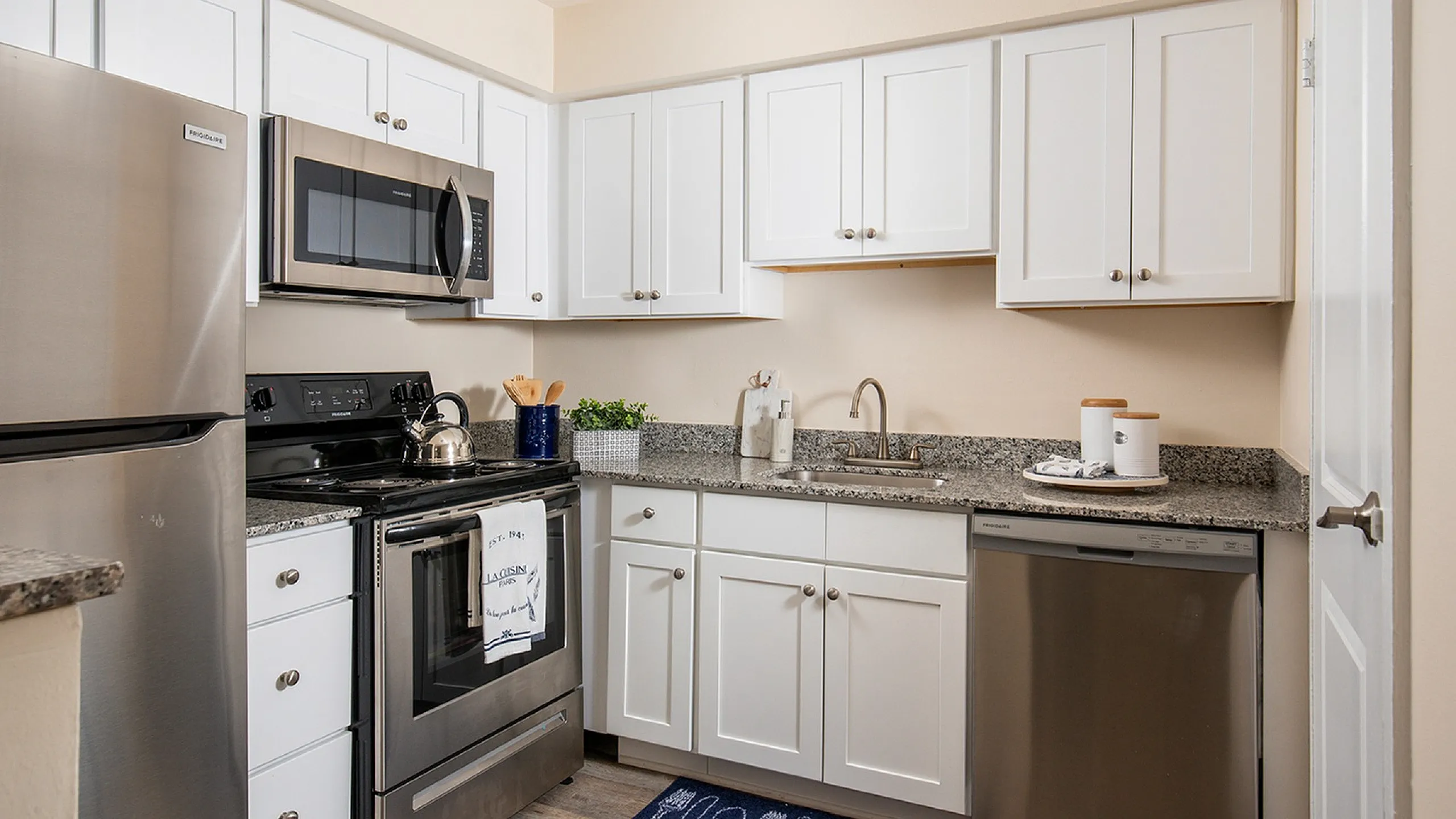 Modern kitchen with sleek stainless steel appliances, white cabinetry, and elegant granite countertops.