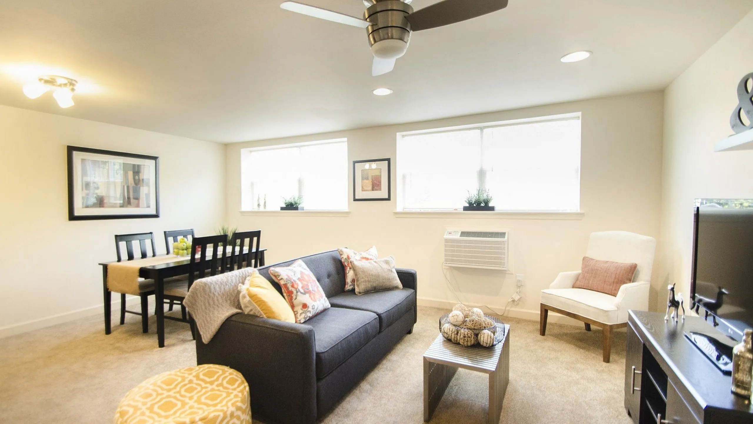 Bright and inviting living room featuring a cozy sofa, modern decor, and a dining area with ample natural light.