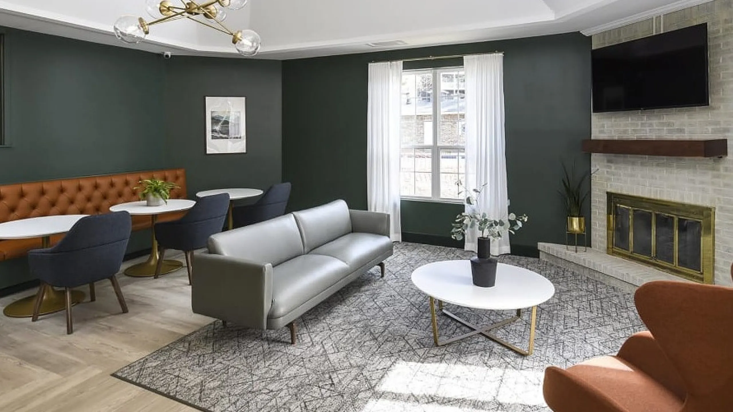 Elegant living area featuring a modern chandelier, cozy seating with plush sofas and chairs, stylish fireplace, and abundant natural light from large windows.