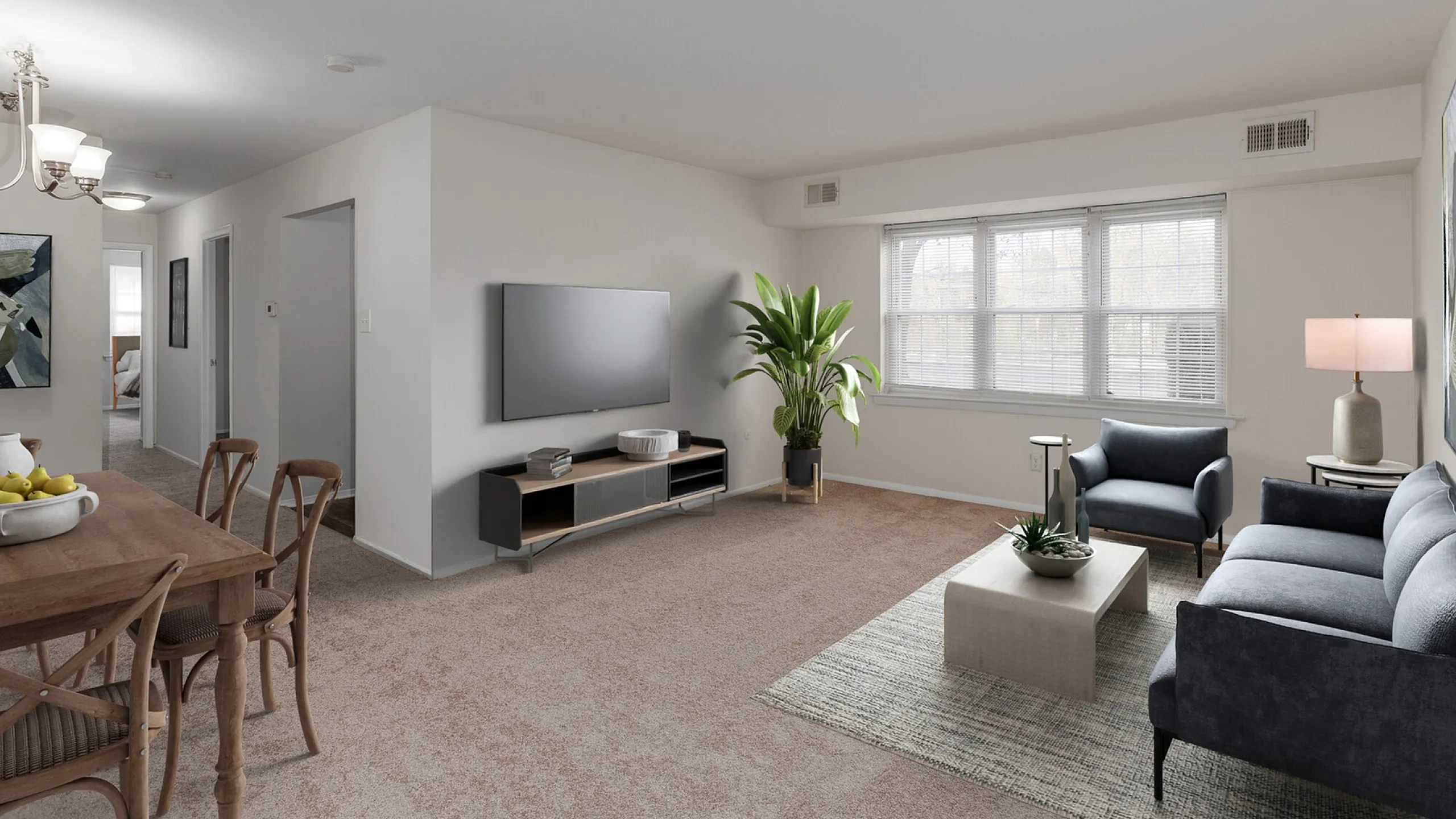Modern living space with plush carpet, elegant wooden dining table, and cozy seating area, complemented by a large TV and abundant natural light.
