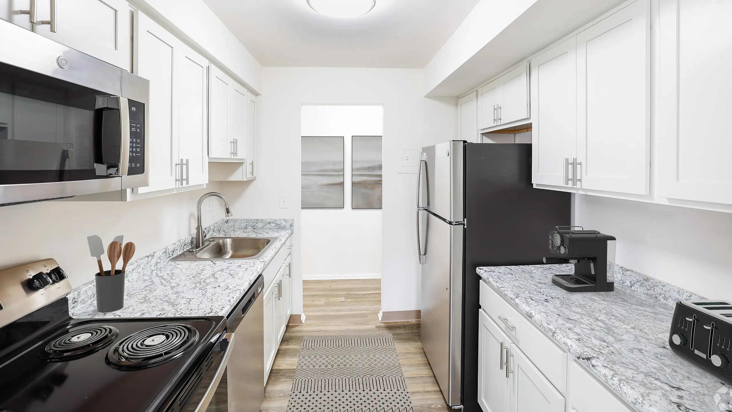 Modern kitchen with sleek white cabinetry, elegant granite countertops, and stainless steel appliances, creating a bright and inviting cooking space.