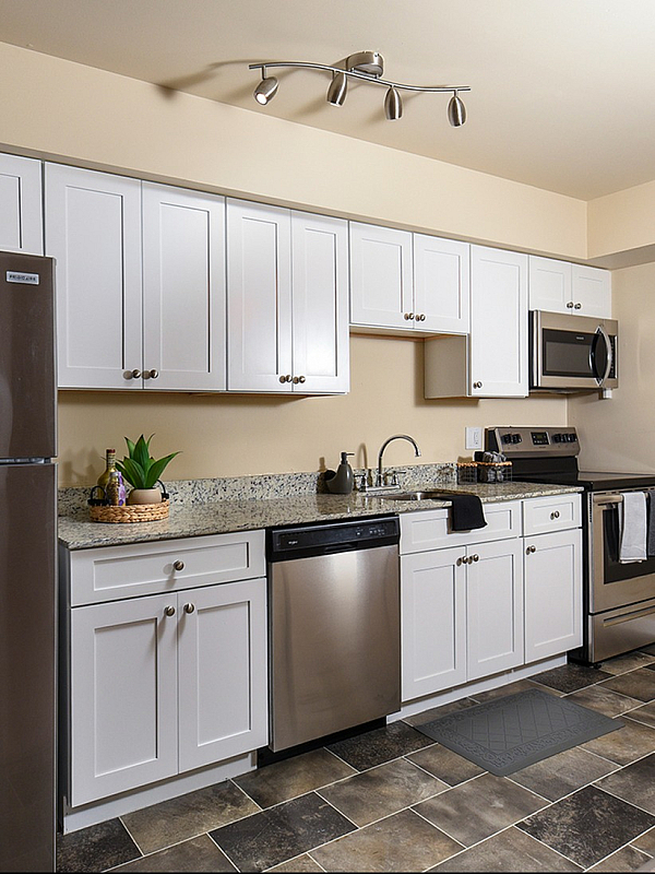 Modern kitchen featuring sleek stainless steel appliances, elegant granite countertops, and stylish white cabinetry with ample storage.