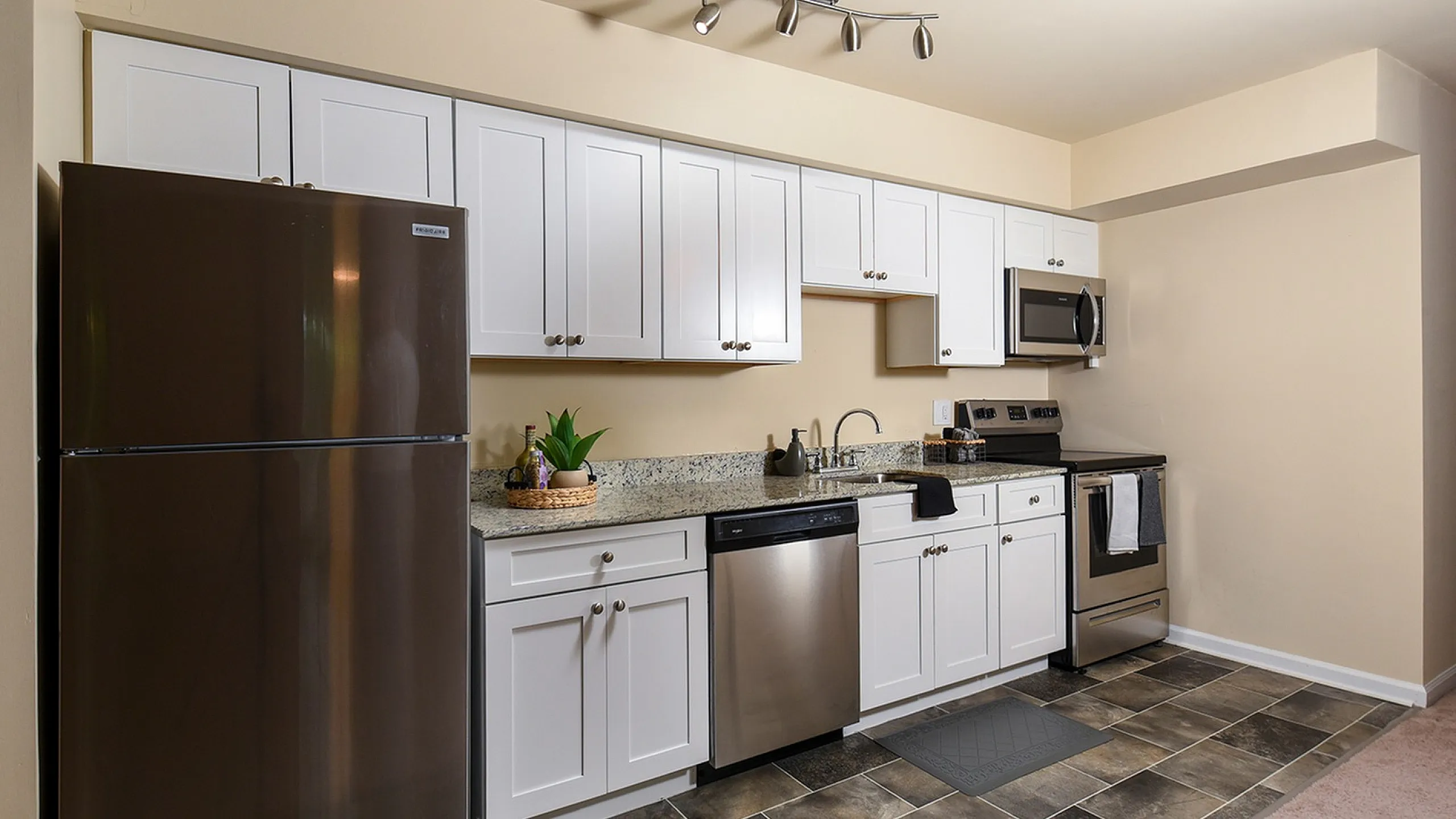 Modern kitchen with sleek stainless steel appliances, granite countertops, and elegant white cabinetry, perfect for culinary enthusiasts.